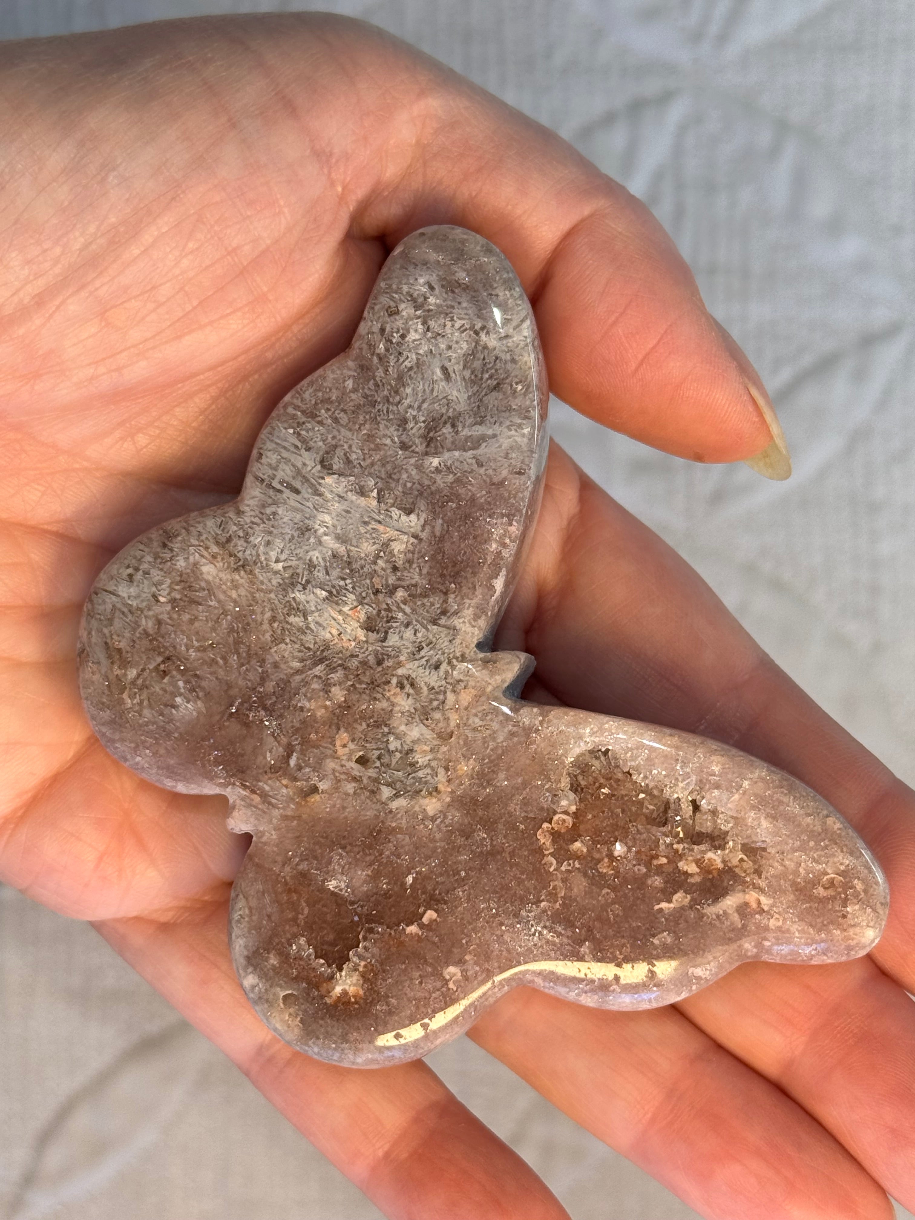 Hand holding a carved crystal butterfly.