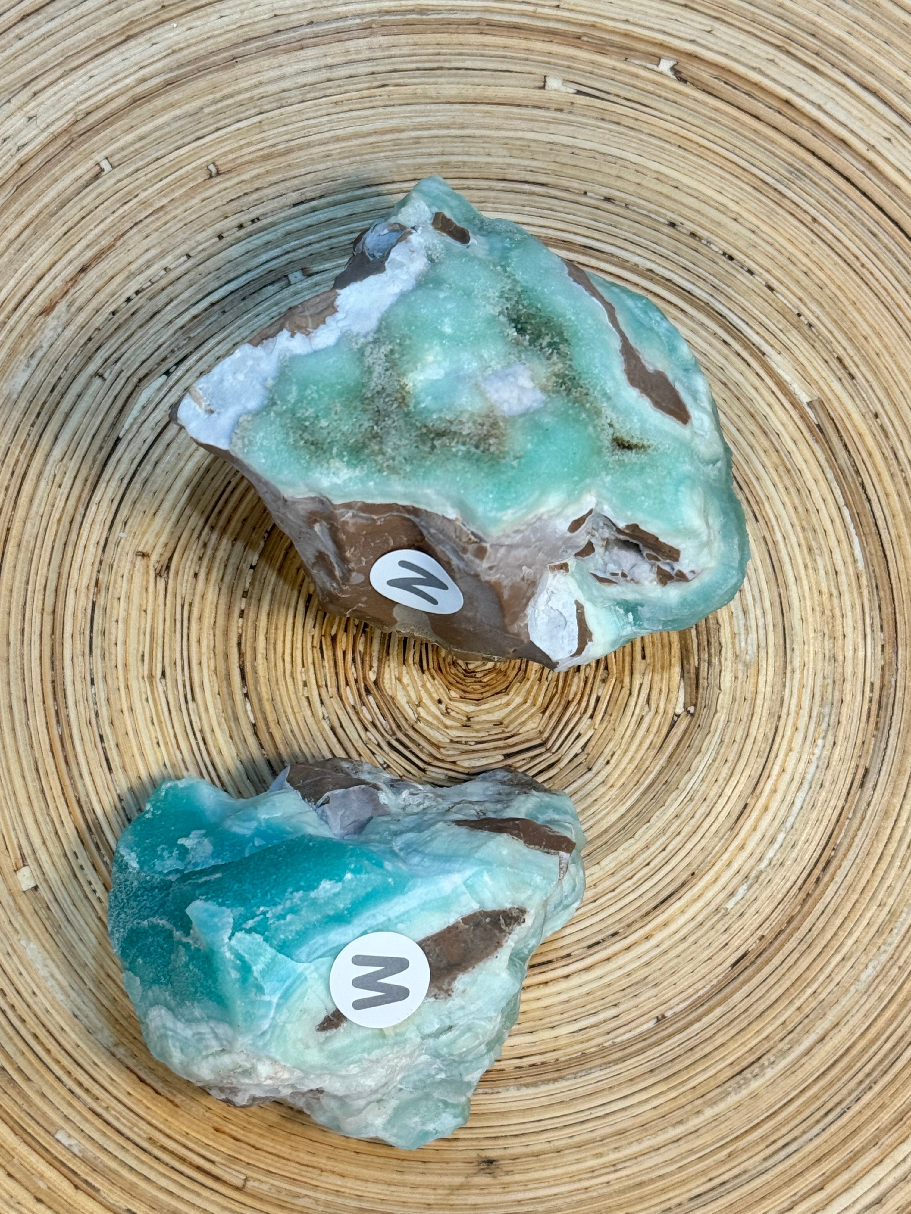 2 raw blue green crystal specimens on a wooden background