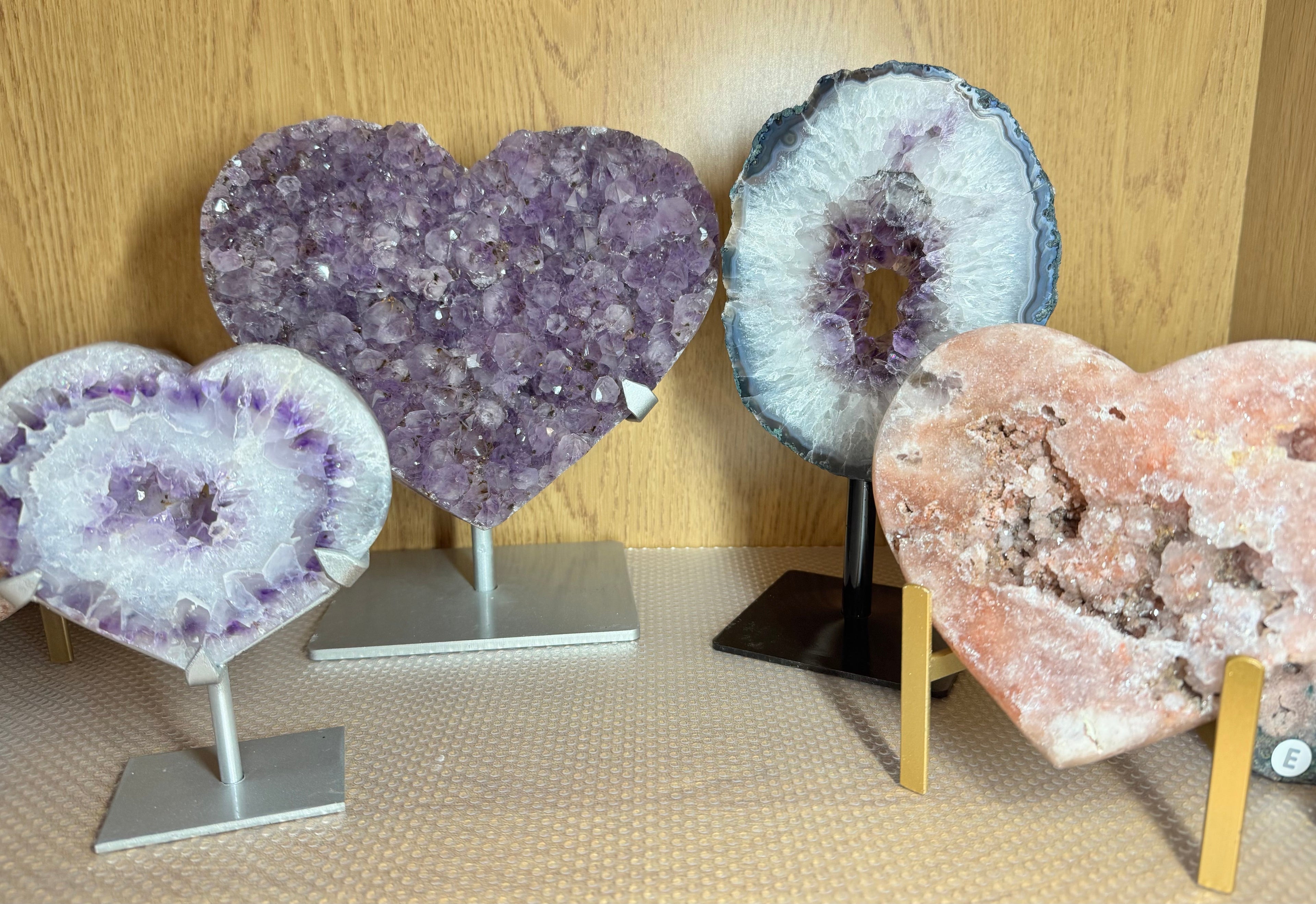 4 statement crystal pieces (amethyst portals and large amethyst hearts, standing on metal stand on a shelf.
