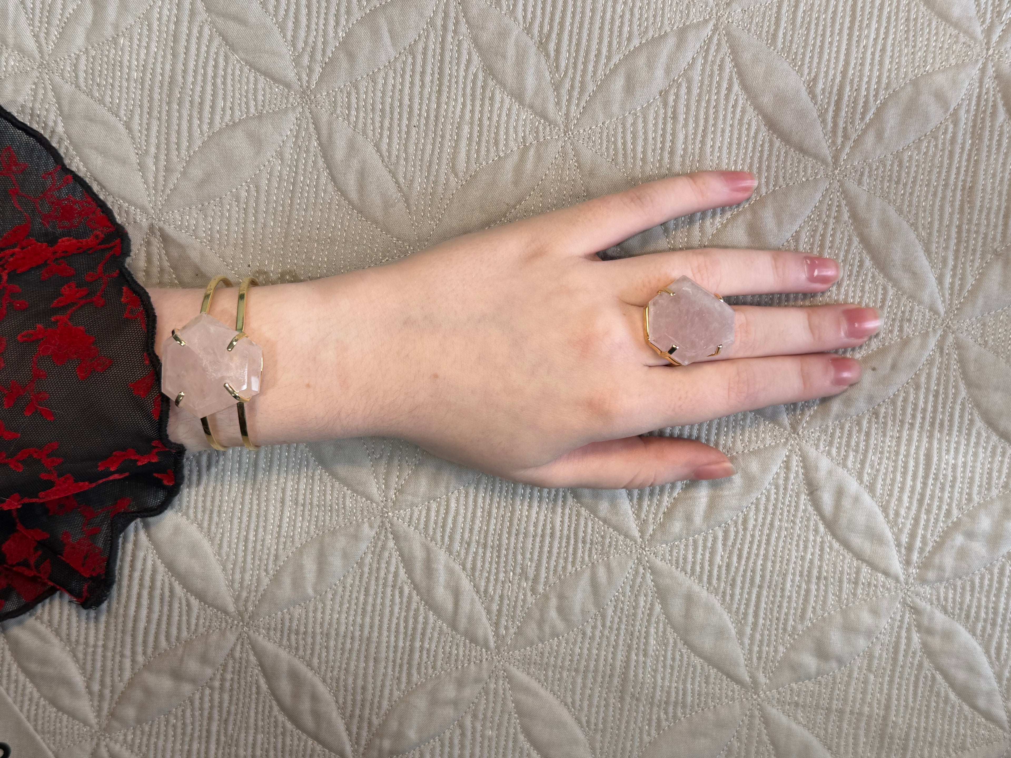 Hand wearing a ring and bracelet on a textured surface