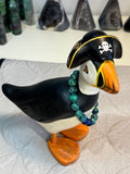 Puffin figurine with pirate hat and beaded necklace on a textured white background