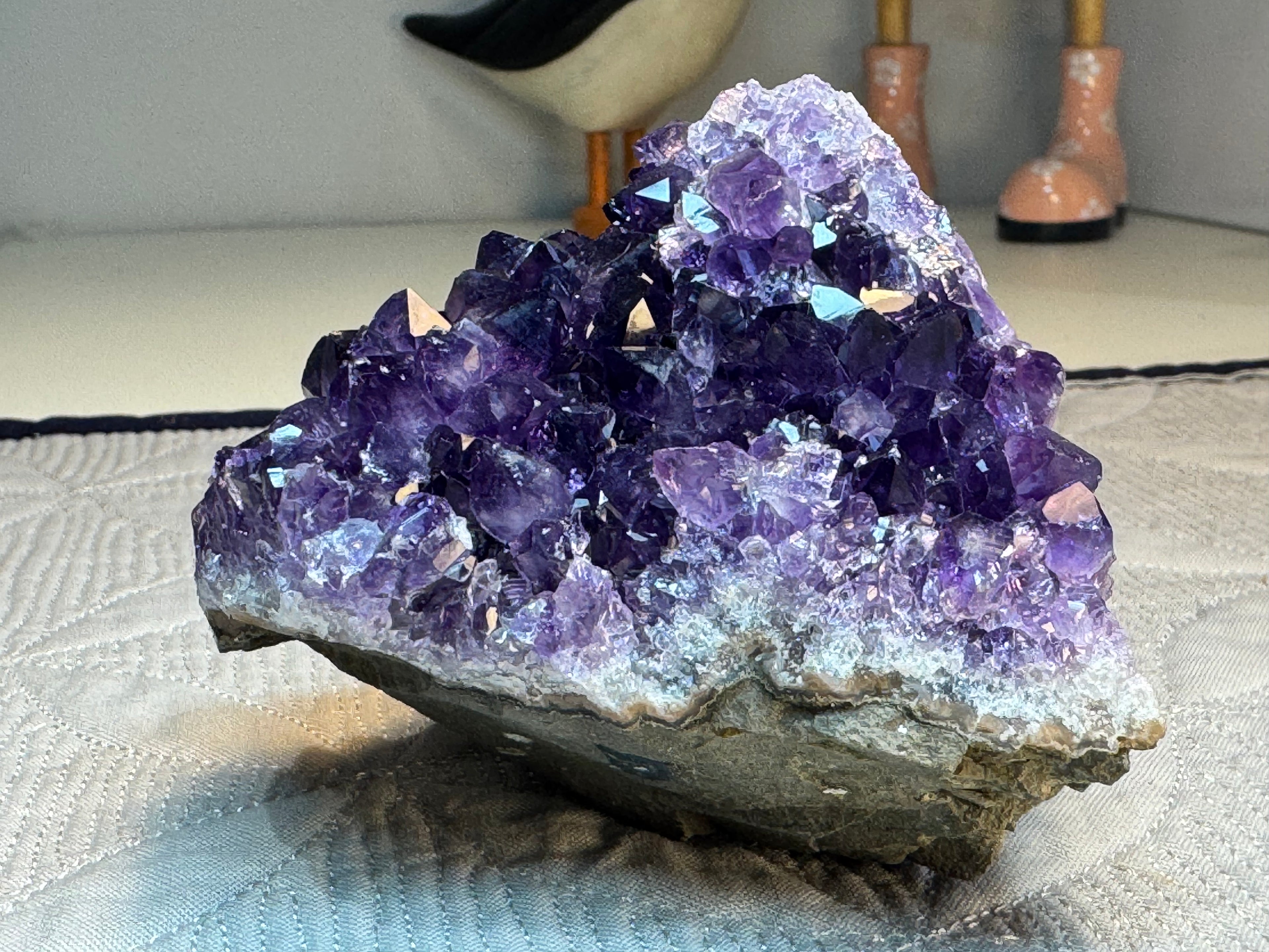 Amethyst crystal cluster on a textured surface with blurred background
