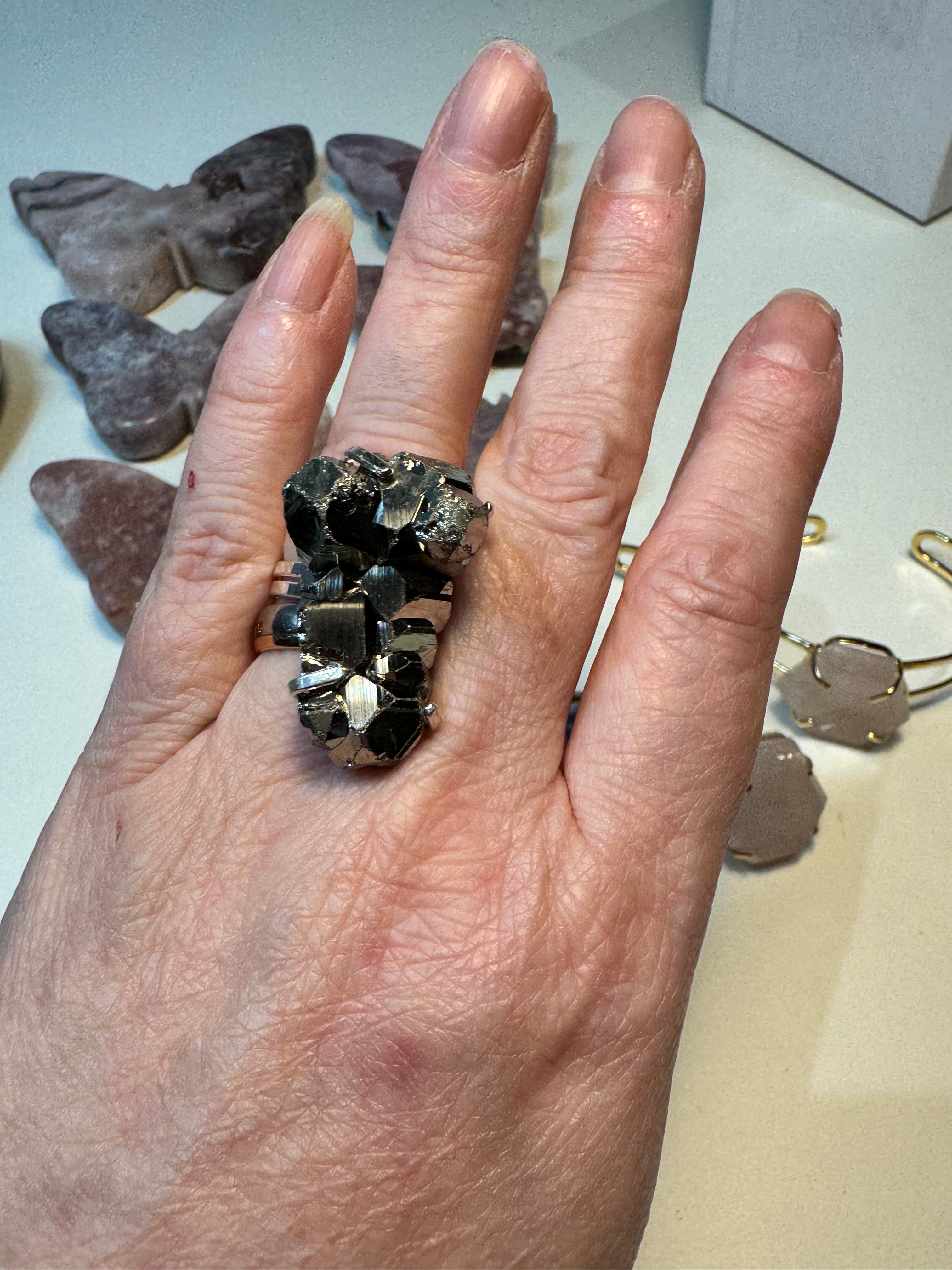 Hand wearing a ring with dark stone on a light background