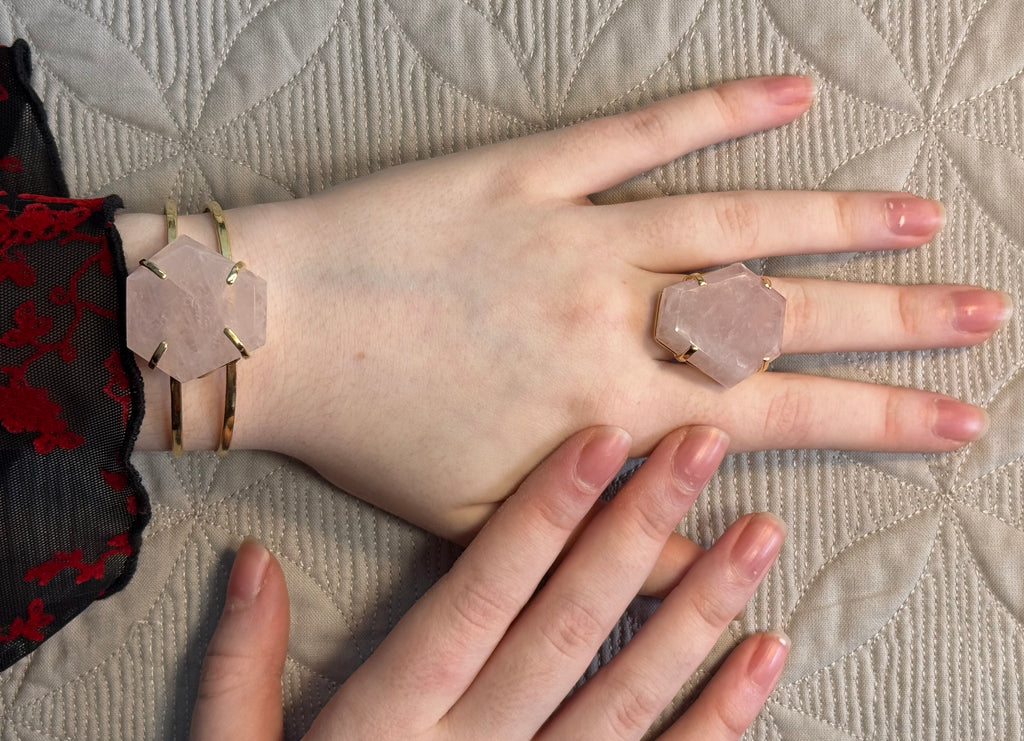 Close-up of hands wearing geometric stone rings on a textured fabric background