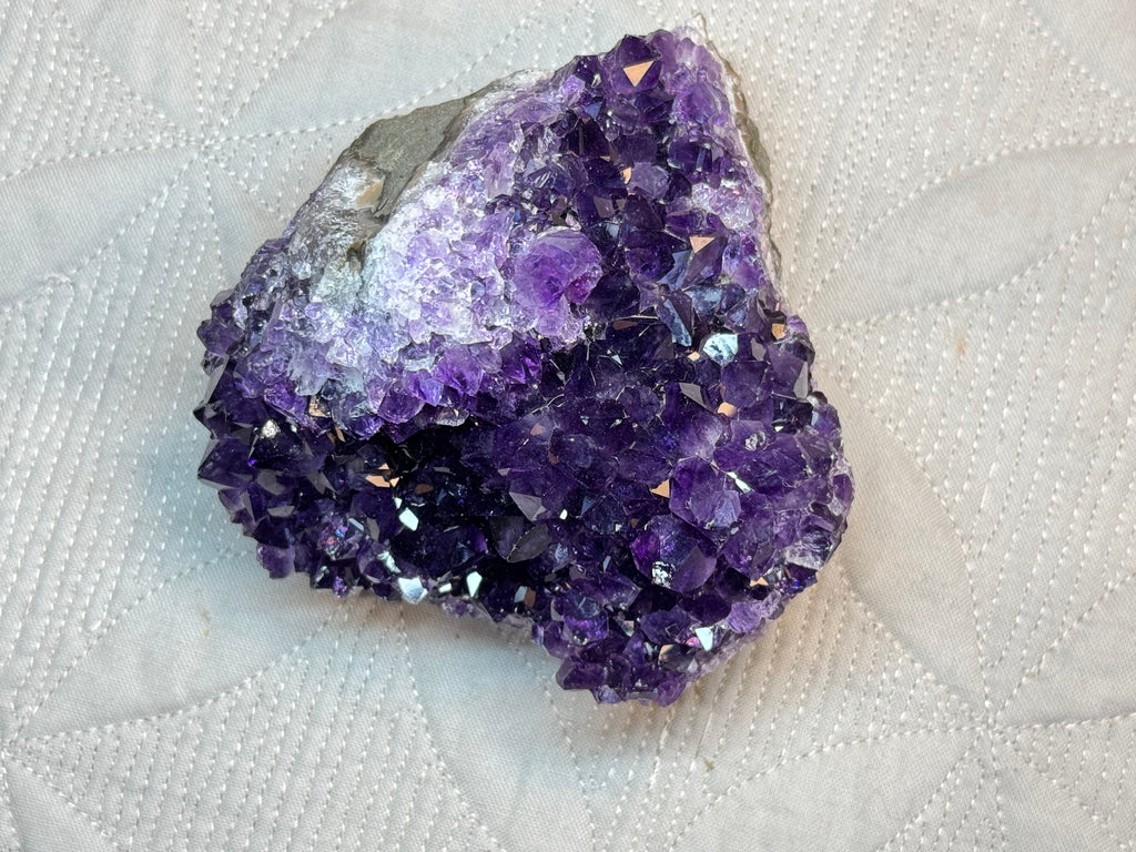Amethyst crystal cluster on a textured white background