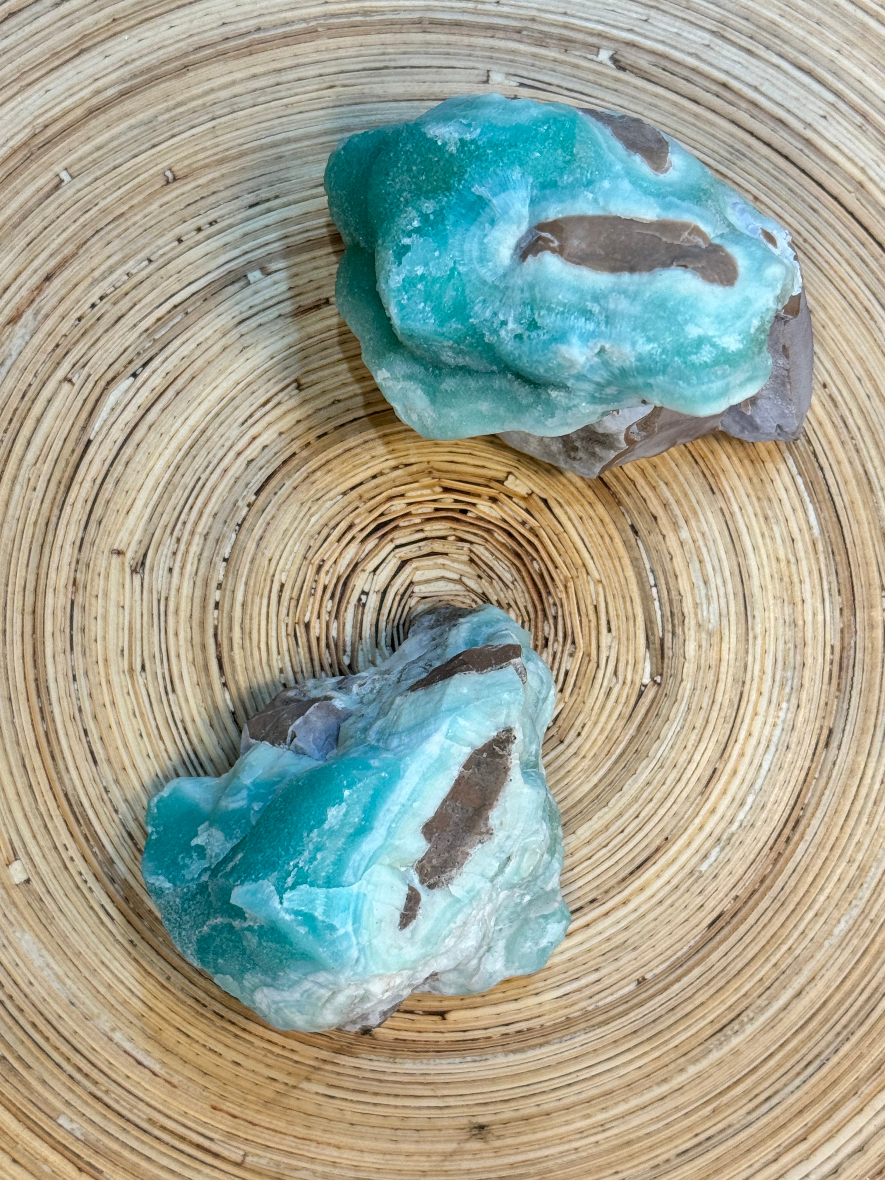 Two blue-green crystals on a woven mat