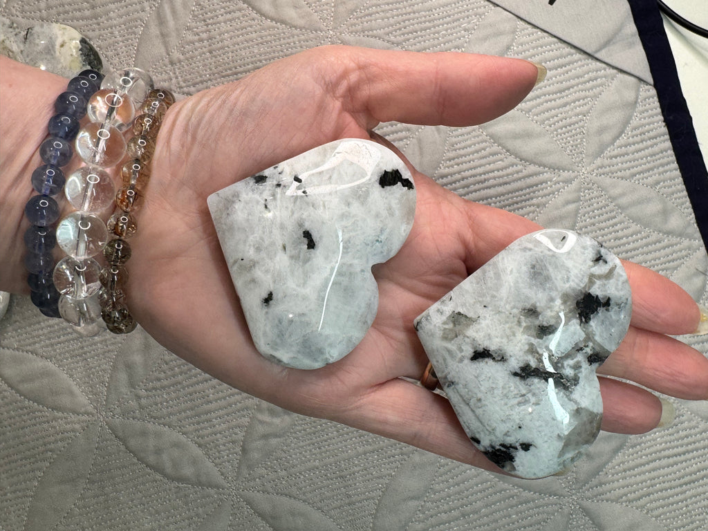 Heart-shaped crystal stones held in a hand with a textured surface background