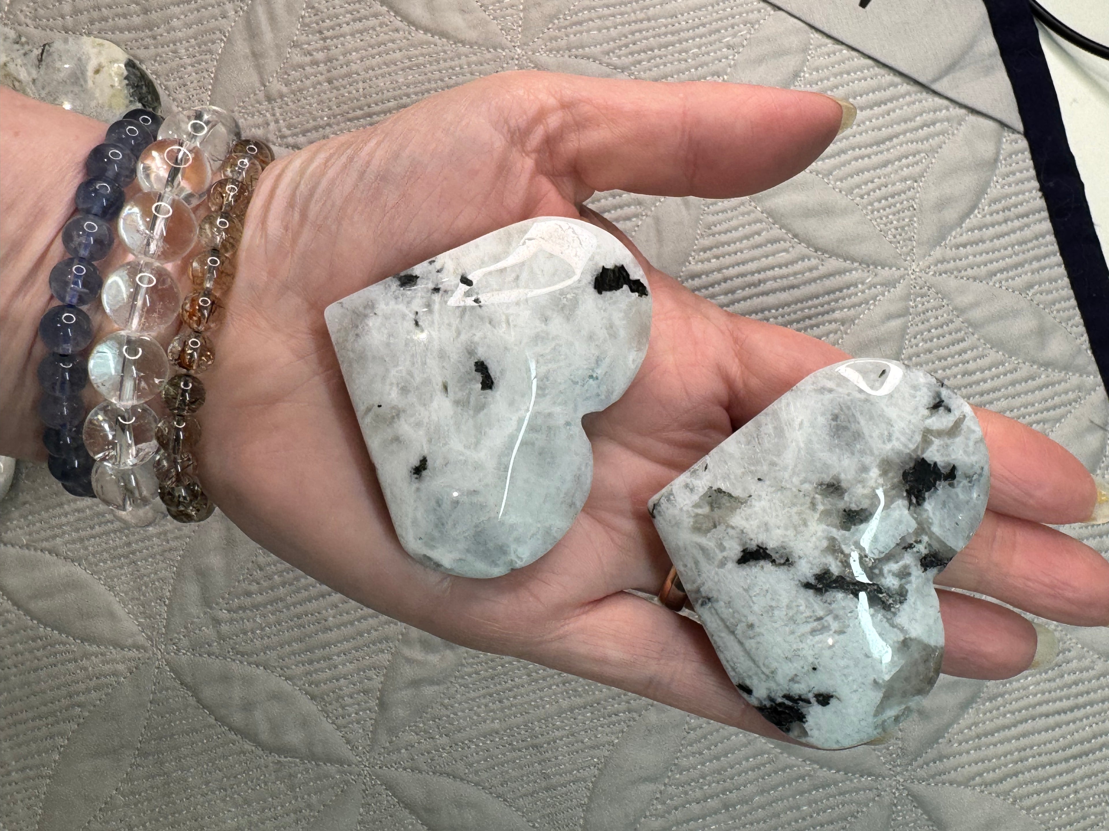 Heart-shaped crystal stones held in a hand with a textured surface background