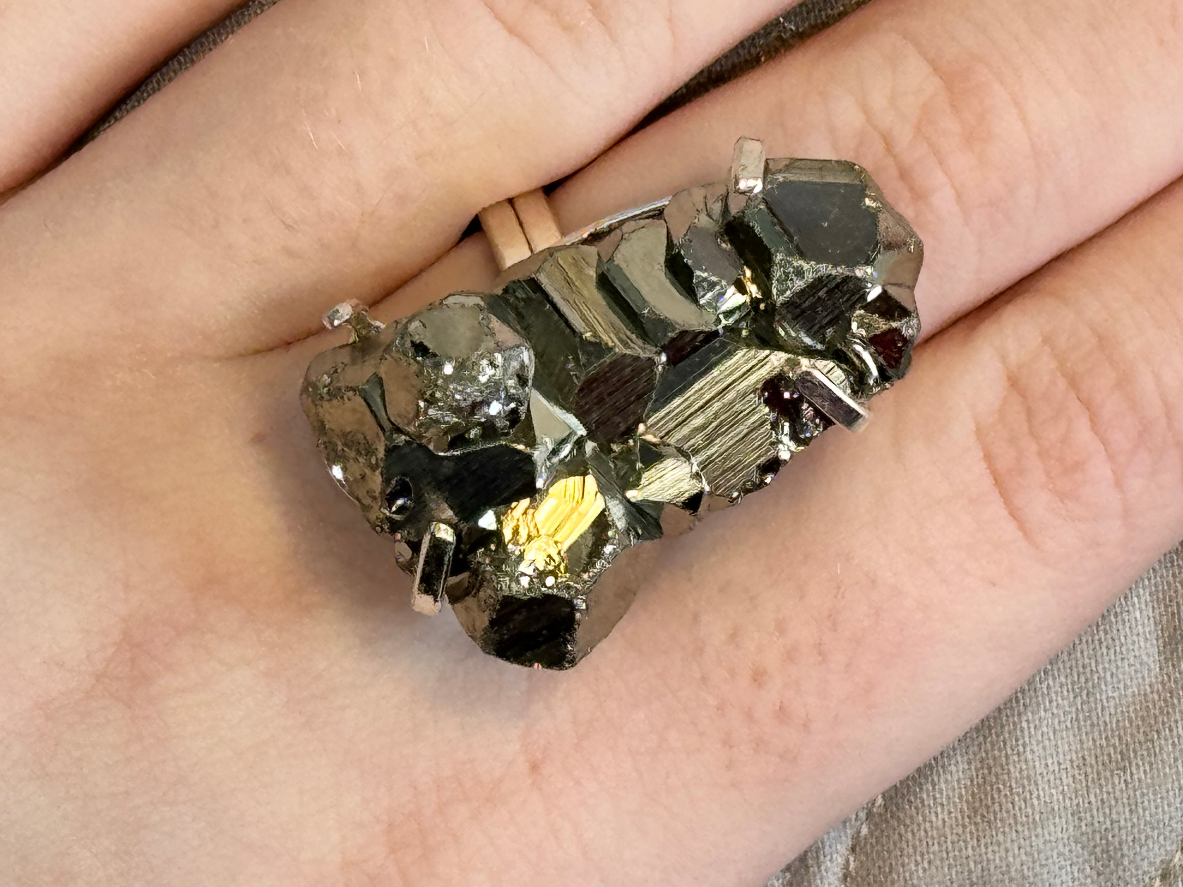 Close-up of a hand wearing a decorative ring with gemstones.