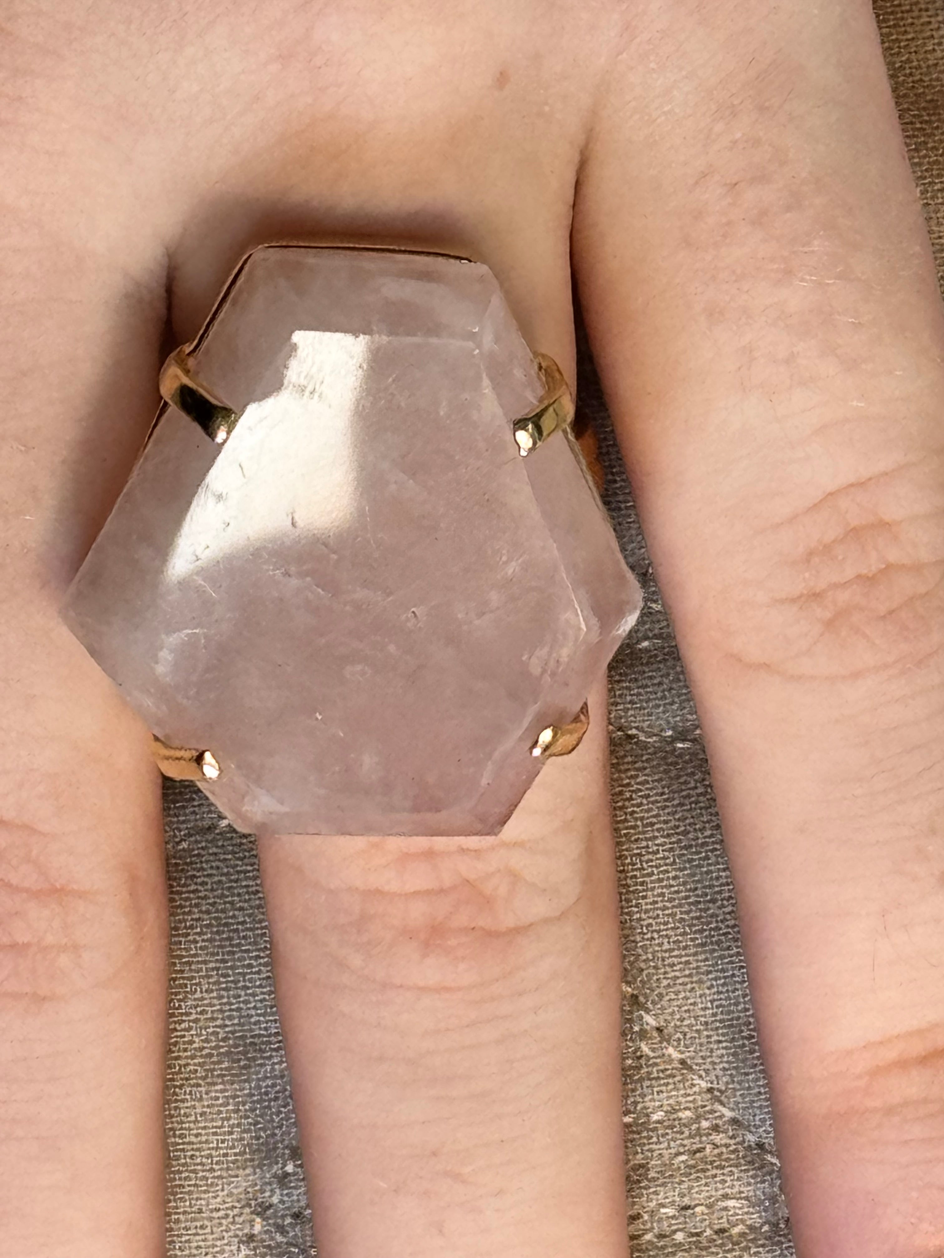 Ring with a pink stone and gold band on a finger