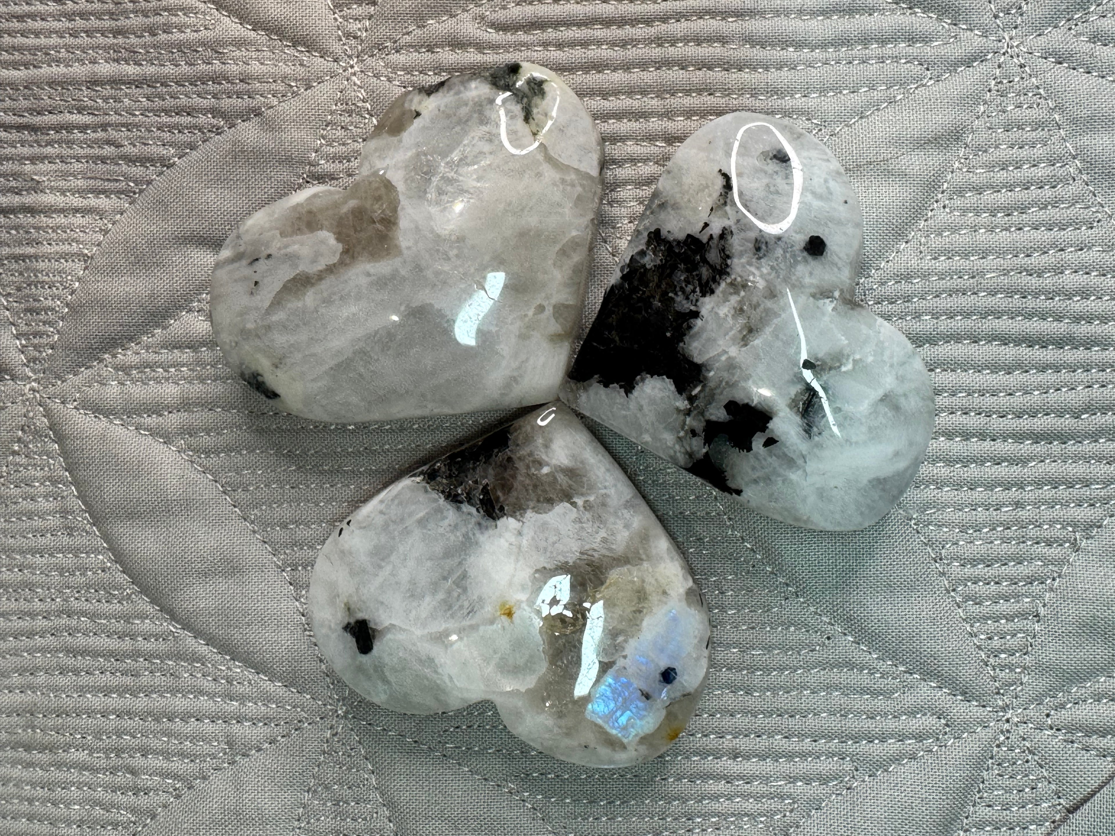 Three heart-shaped stones with a patterned fabric background