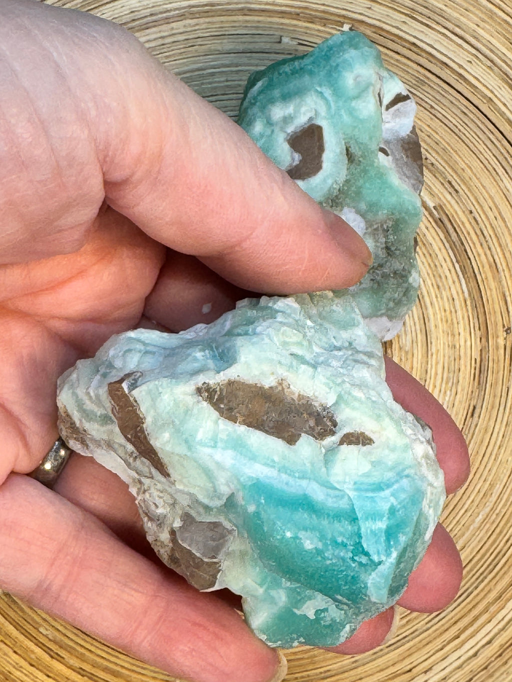 Hand holding a rough turquoise stone on a wooden surface
