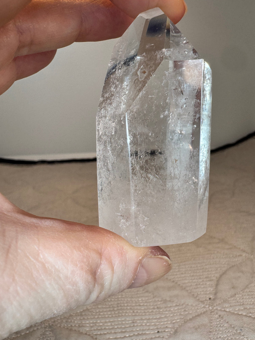 Clear crystal held between fingers against a neutral background