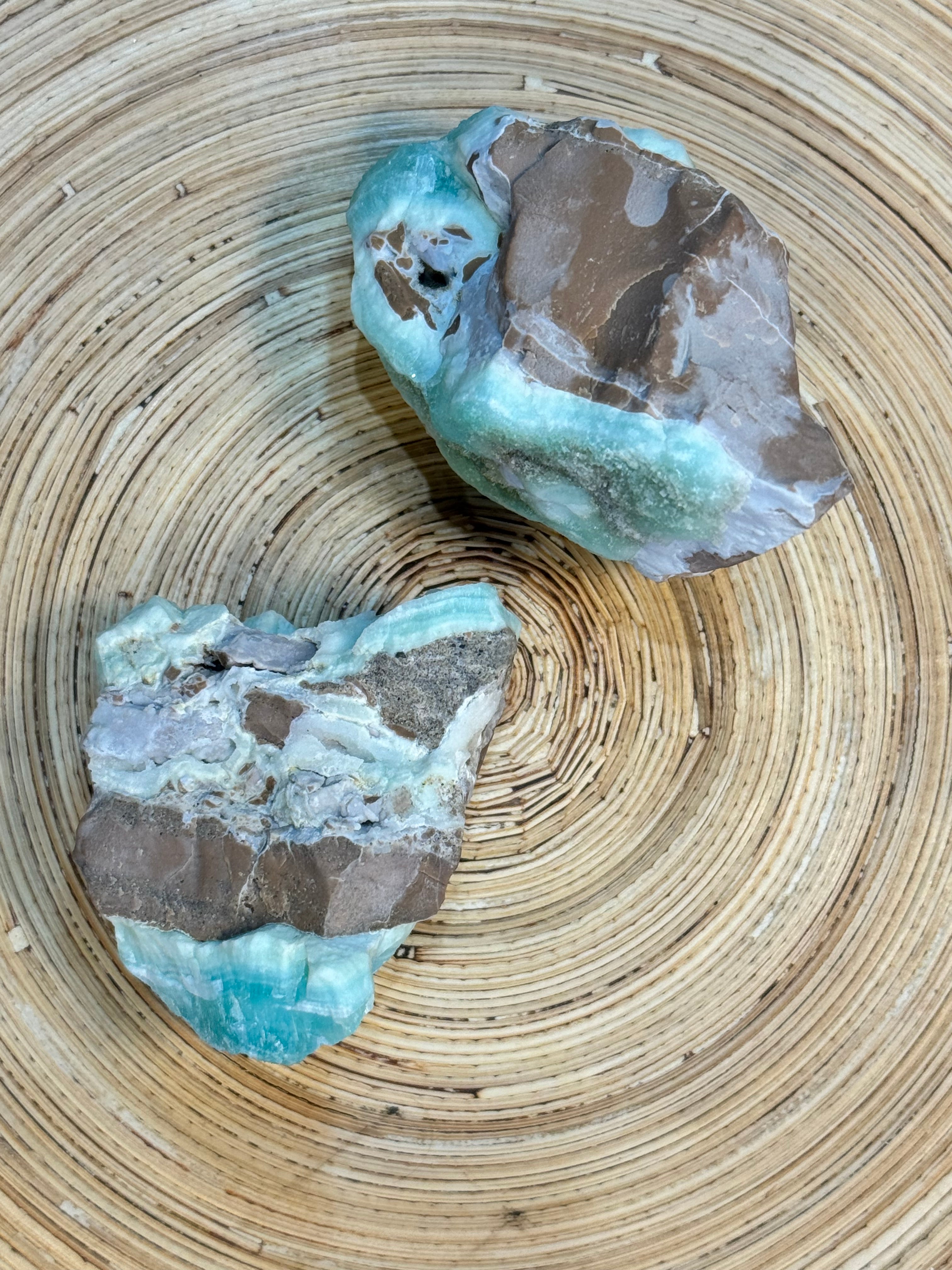 Two rough gemstones on a woven surface
