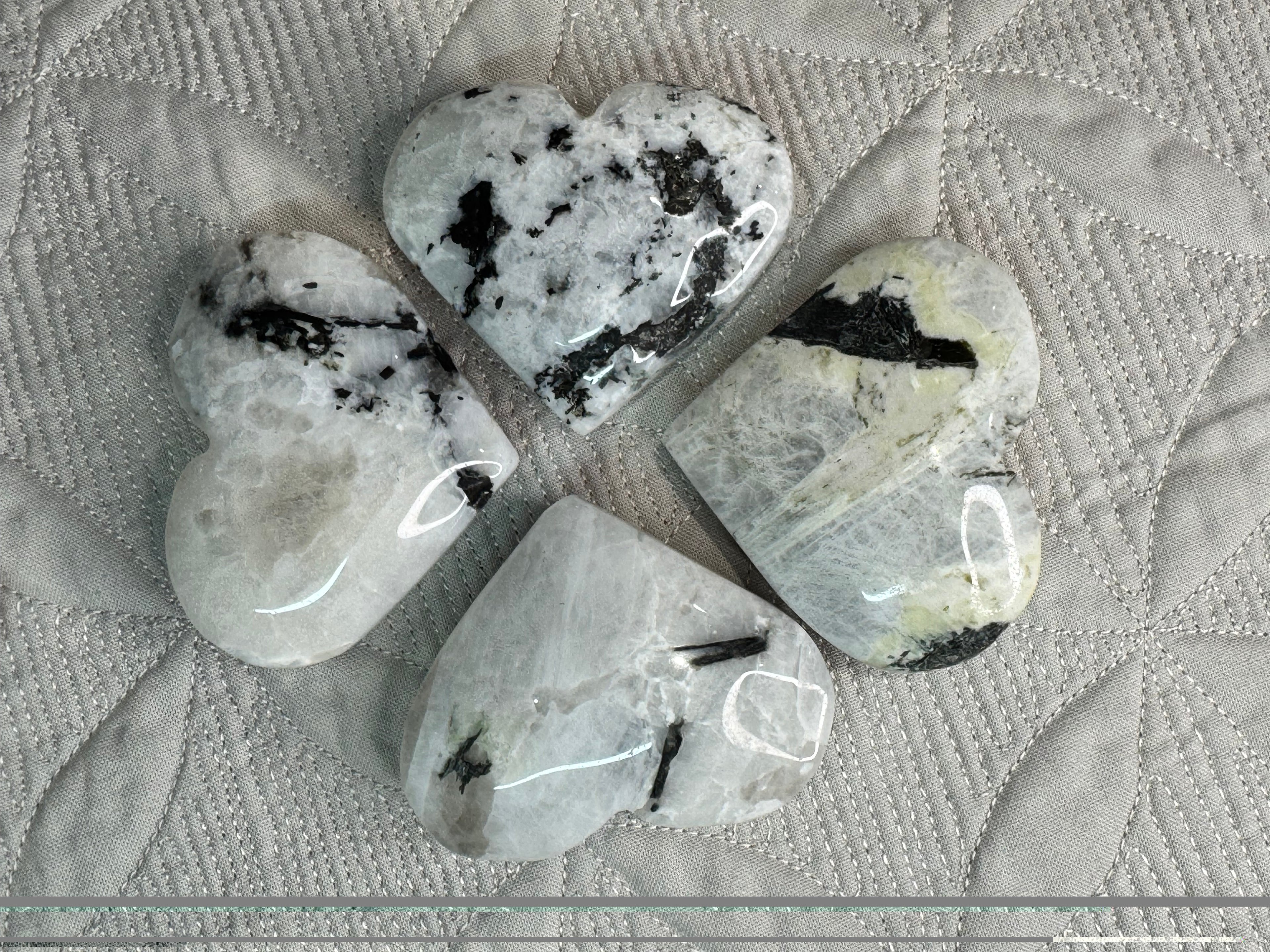 Heart-shaped stones with black markings on a textured fabric background