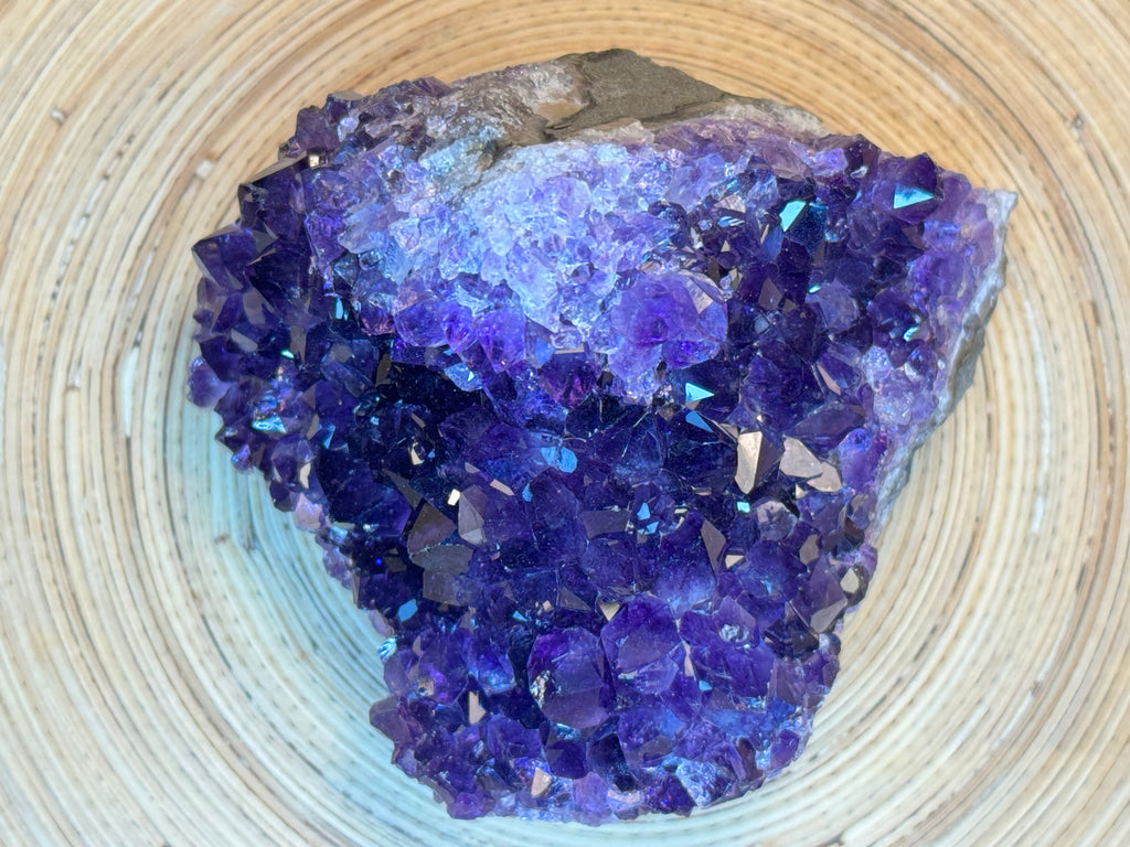 Amethyst crystal cluster on a woven surface
