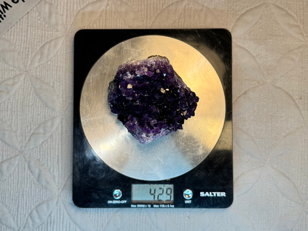 Amethyst crystal on a Salter digital kitchen scale with a beige background