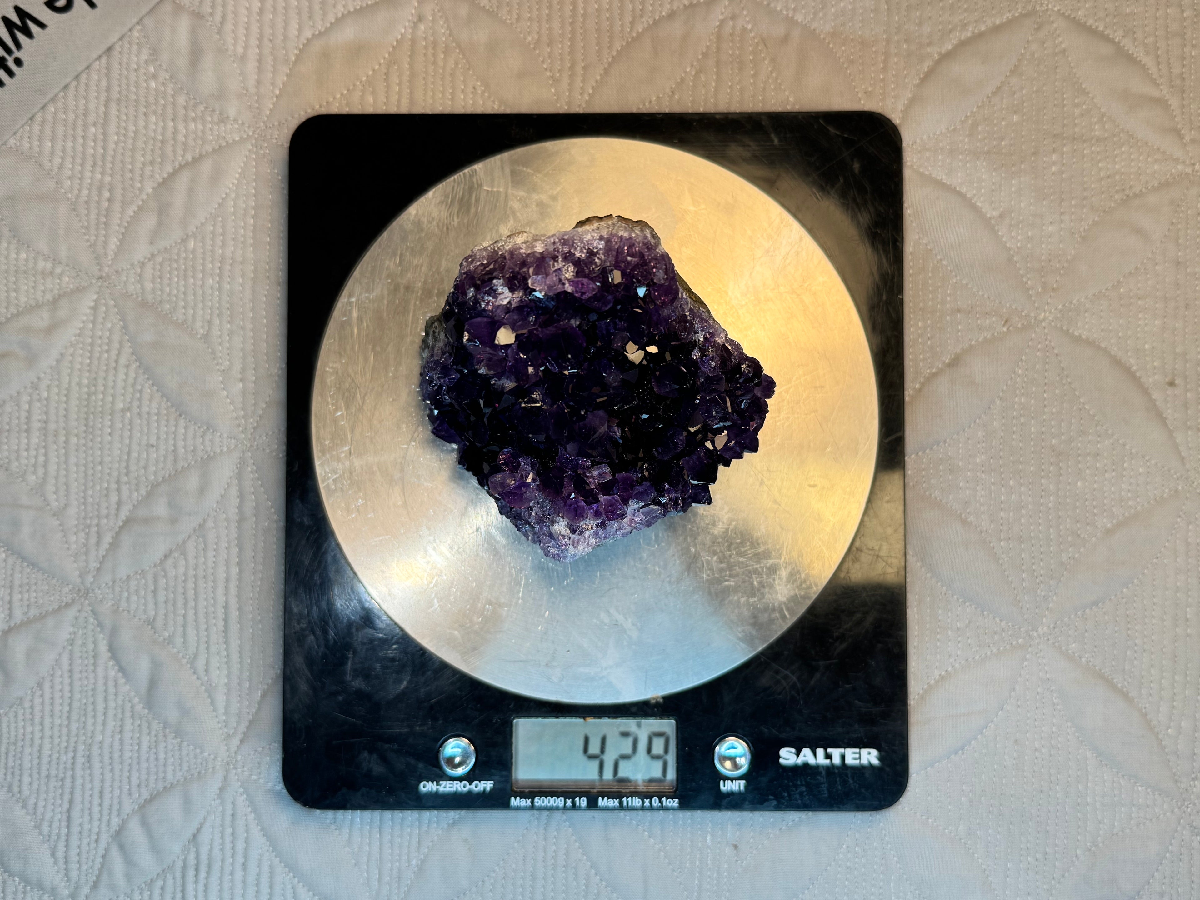 Amethyst crystal on a Salter digital kitchen scale with a beige background