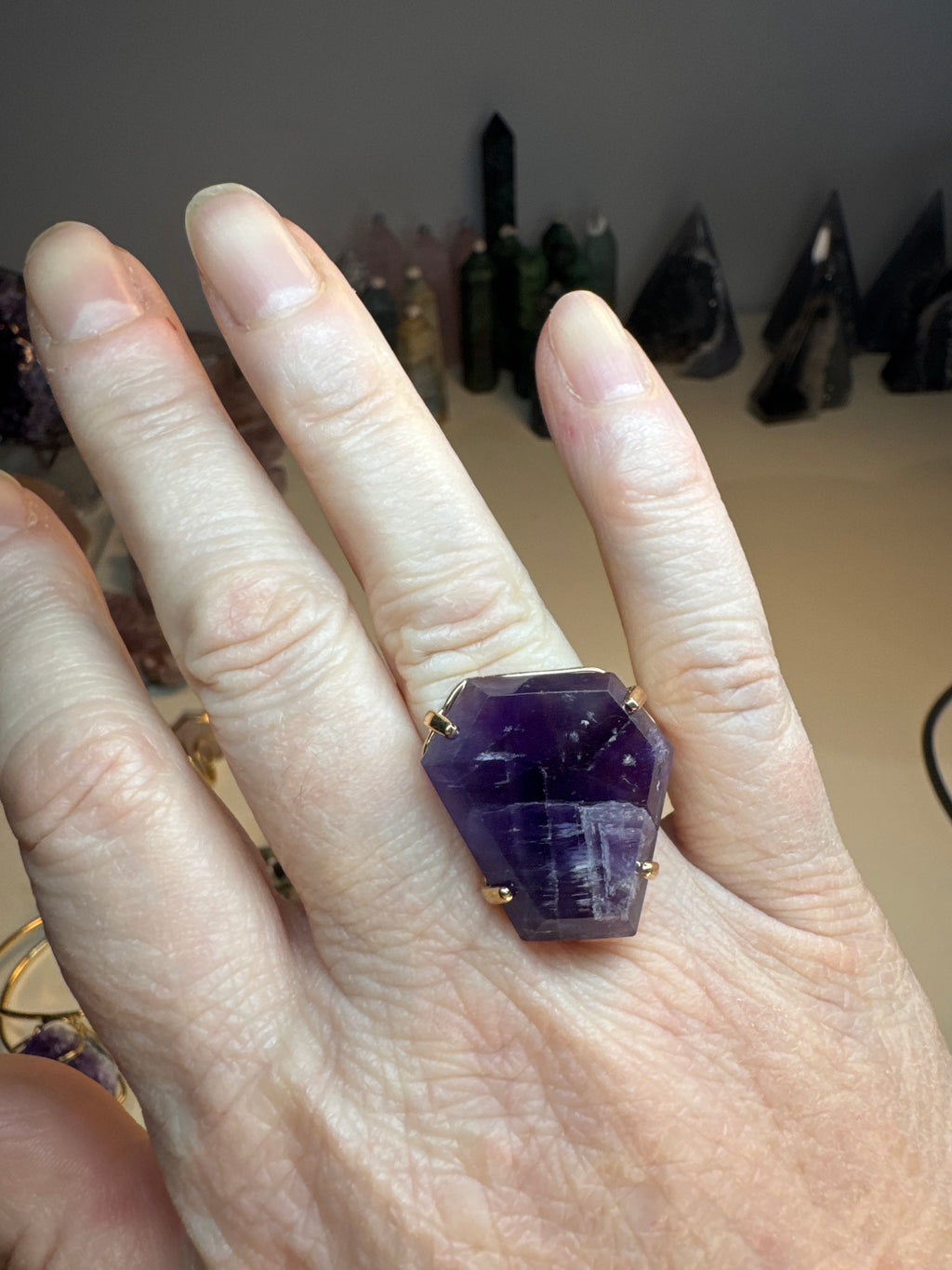 Hand wearing a purple crystal ring with a blurred background