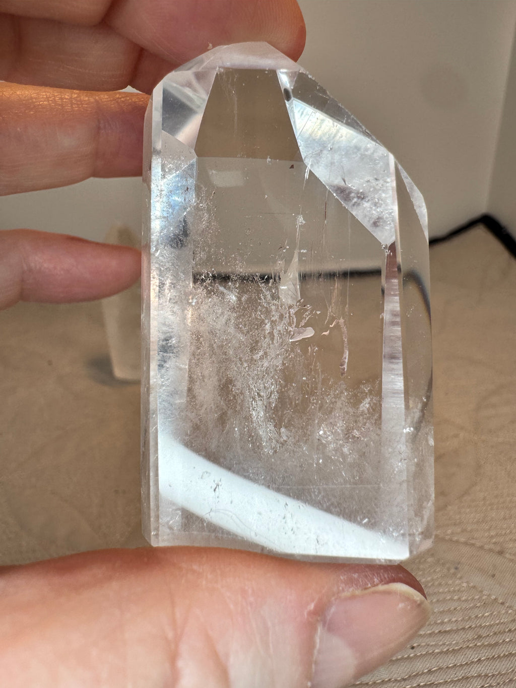 Clear crystal held between fingers against a neutral background