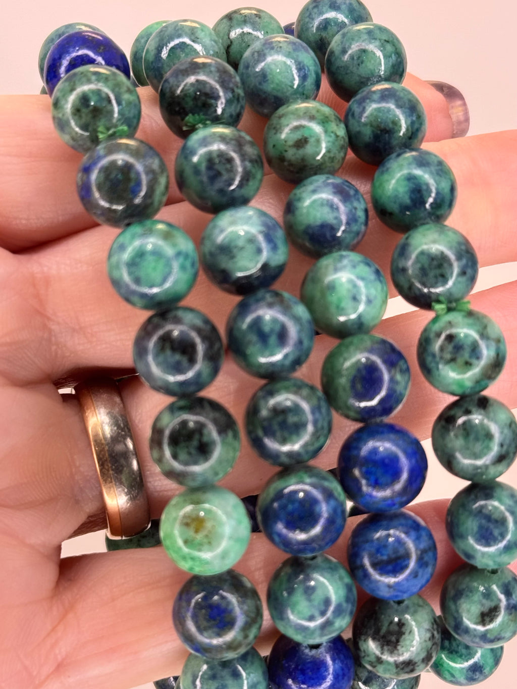 Close-up of green and blue beaded bracelets on a hand