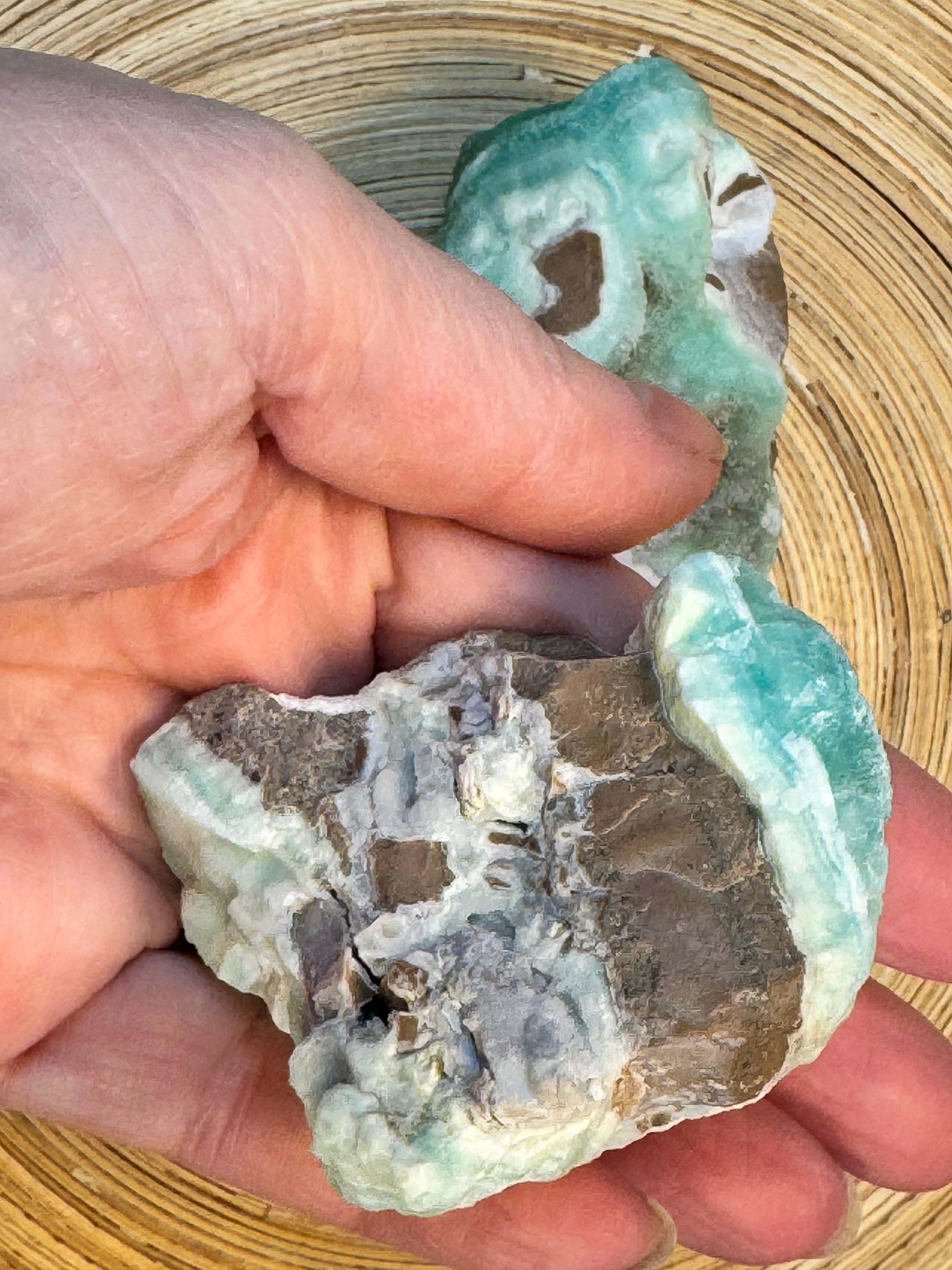 Hand holding a rough piece of turquoise stone on a woven surface