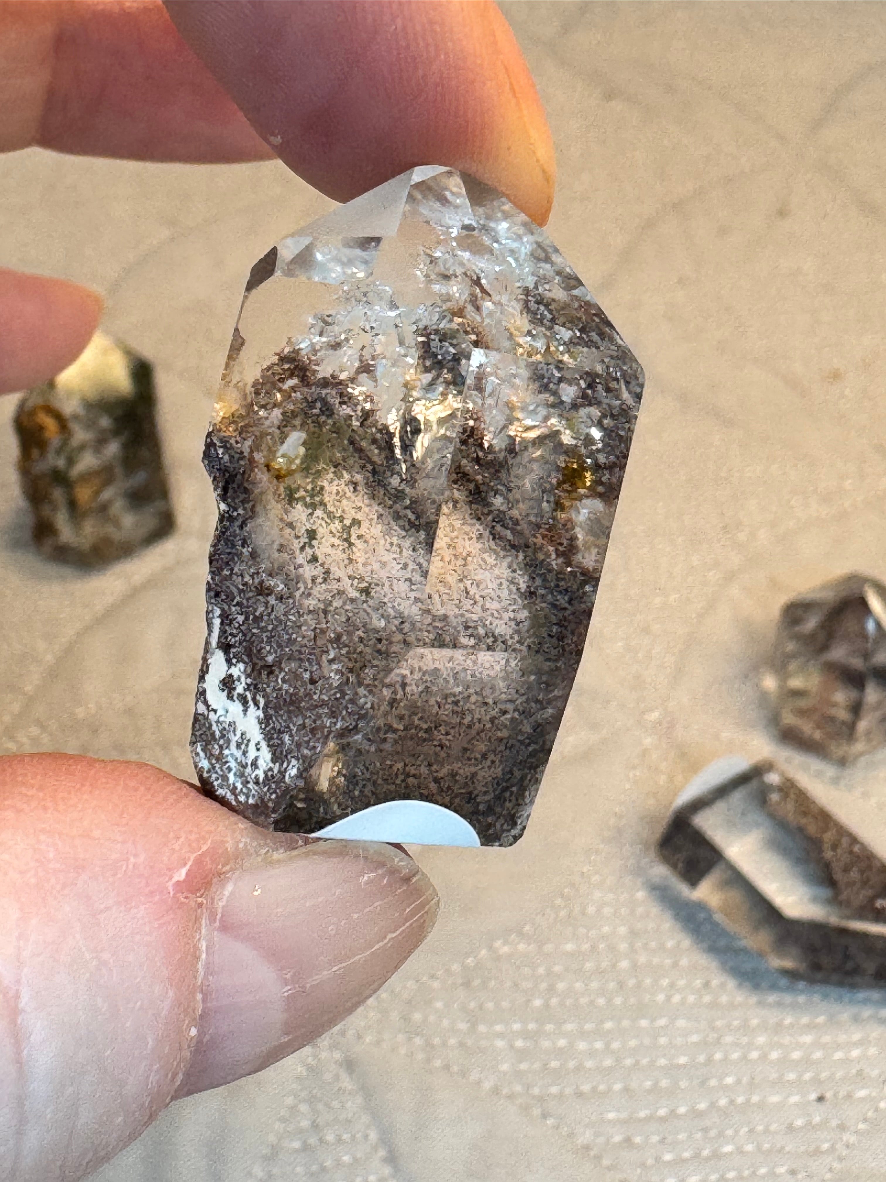 Raw diamond held between fingers with a blurred background