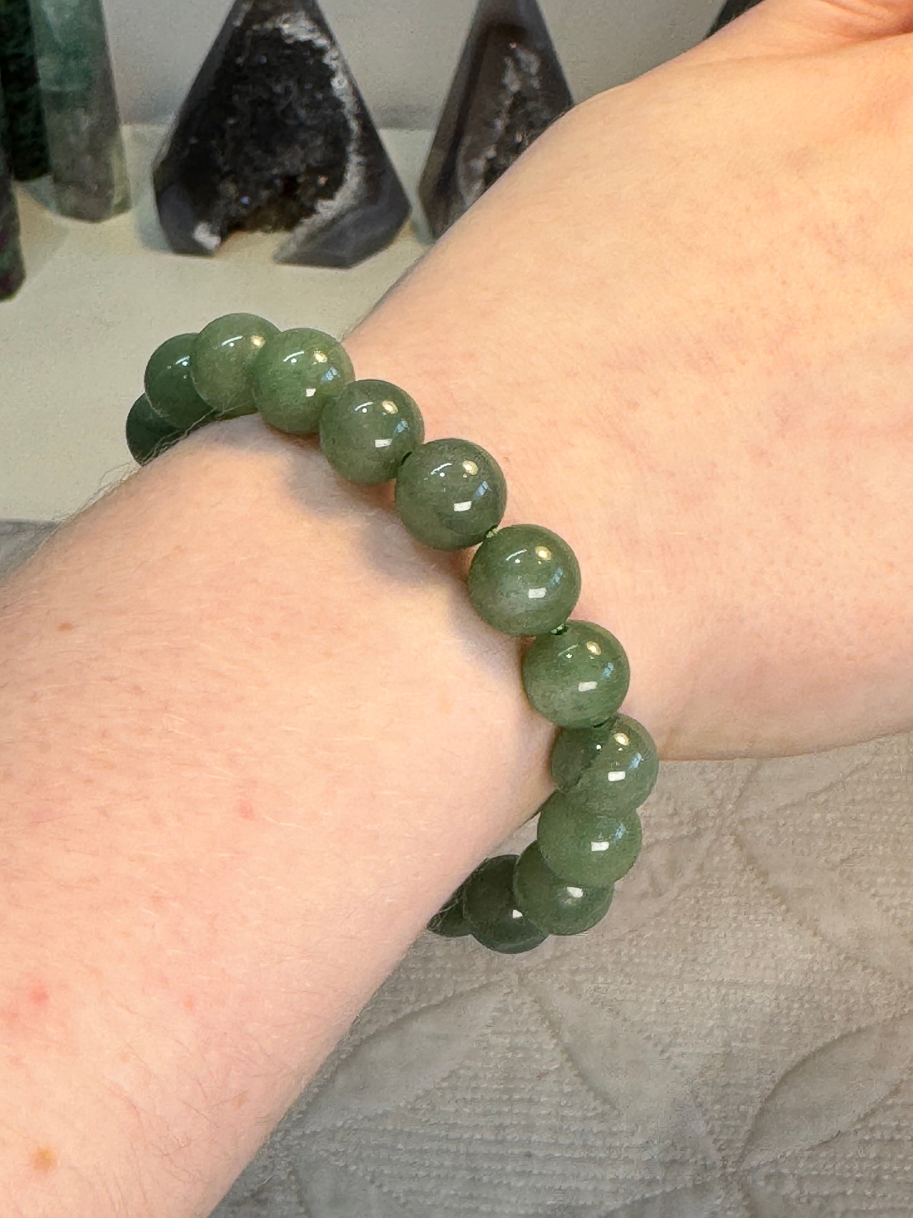 Green beaded bracelet on a wrist with a blurred background