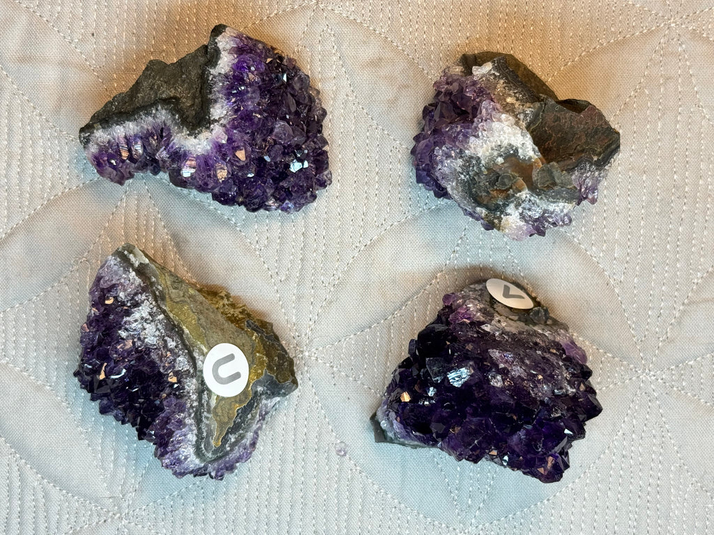 Four amethyst crystals on a textured white surface