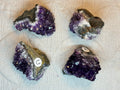 Four amethyst crystals on a textured white surface