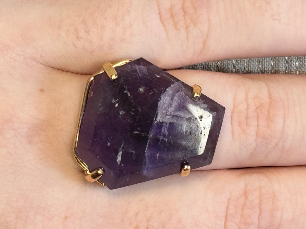 Amethyst ring with gold band on a finger