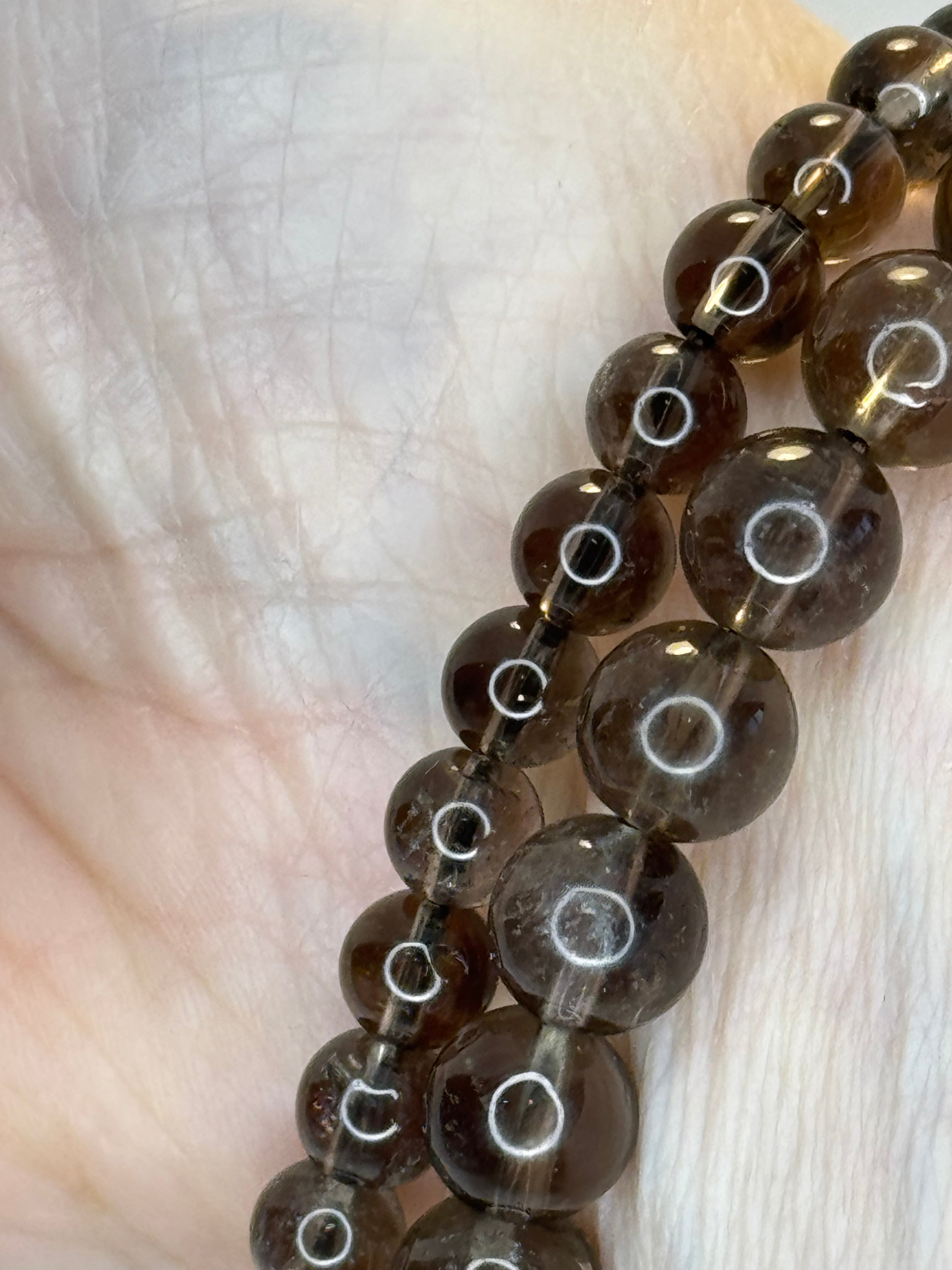 Close-up of a string of brown beads on a light skin surface