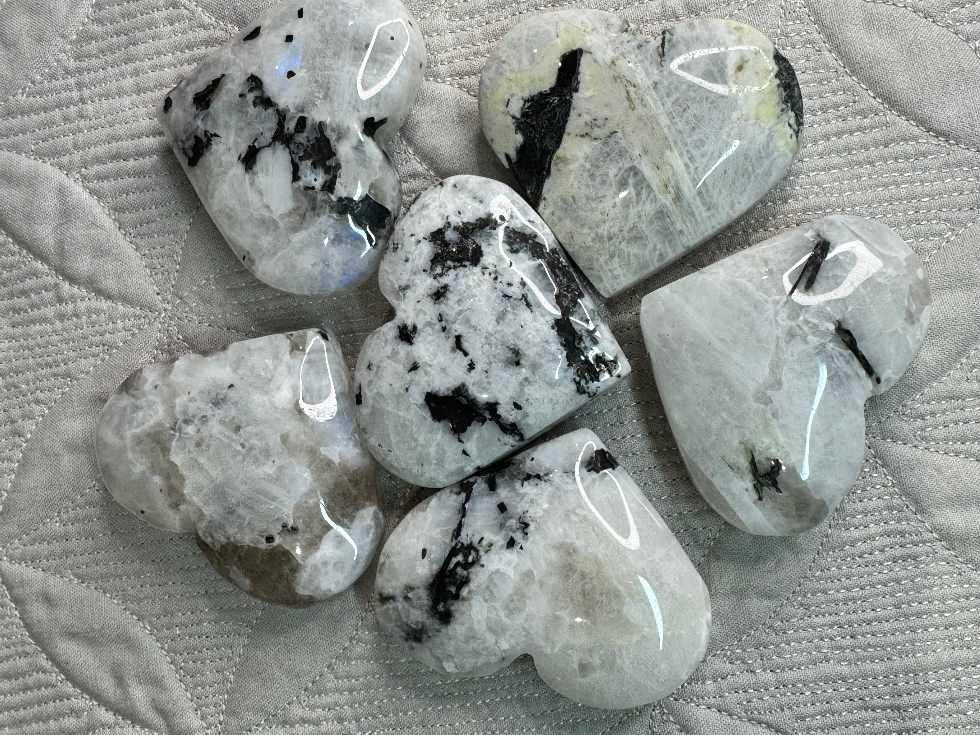 6 Heart-shaped stones with black inclusions on a textured surface