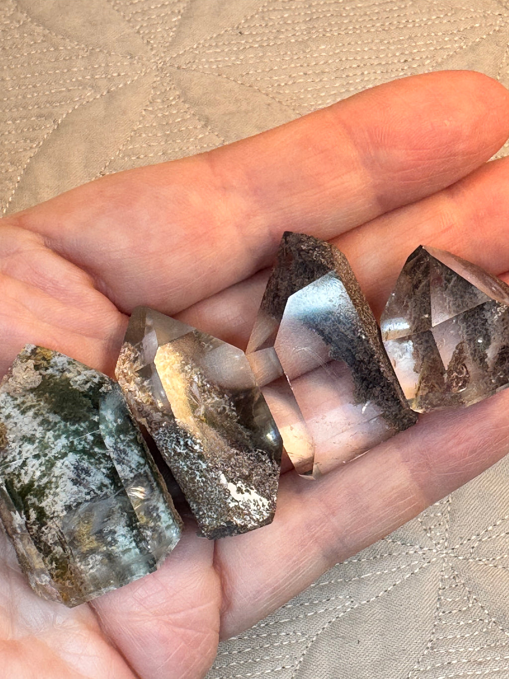 Hand holding a stack of crystal-like rocks on a textured beige surface
