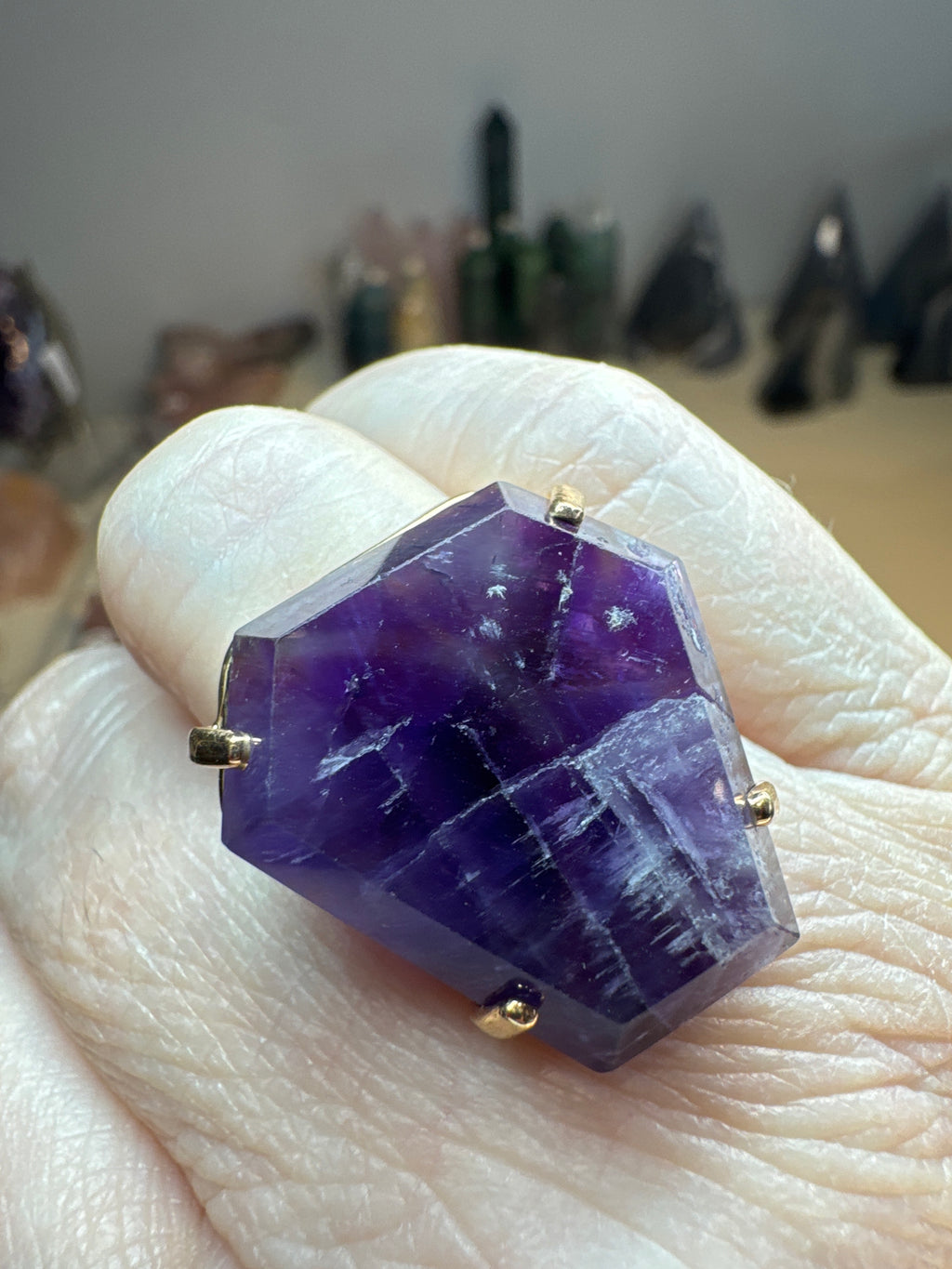 Amethyst ring held by a gloved hand with blurred background