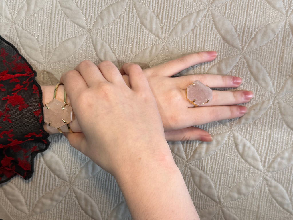 Two hands wearing rings on a textured fabric background