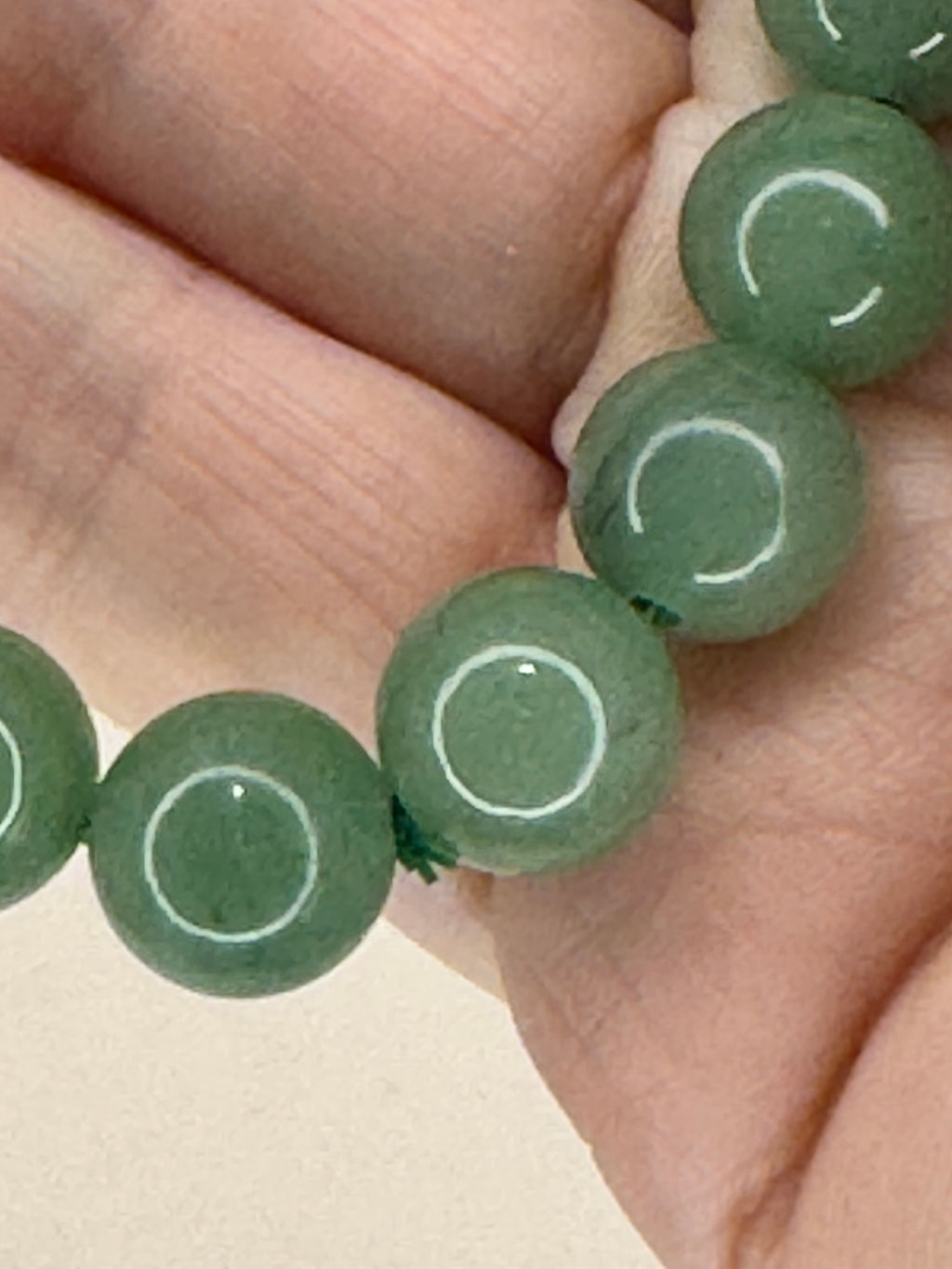 Close-up of green beads with white patterns on a beige background