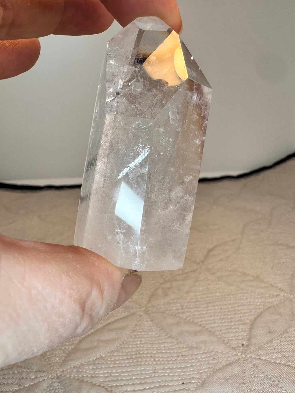 Clear crystal held between fingers against a neutral background
