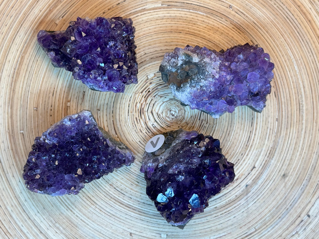 Four purple amethyst crystals on a woven surface