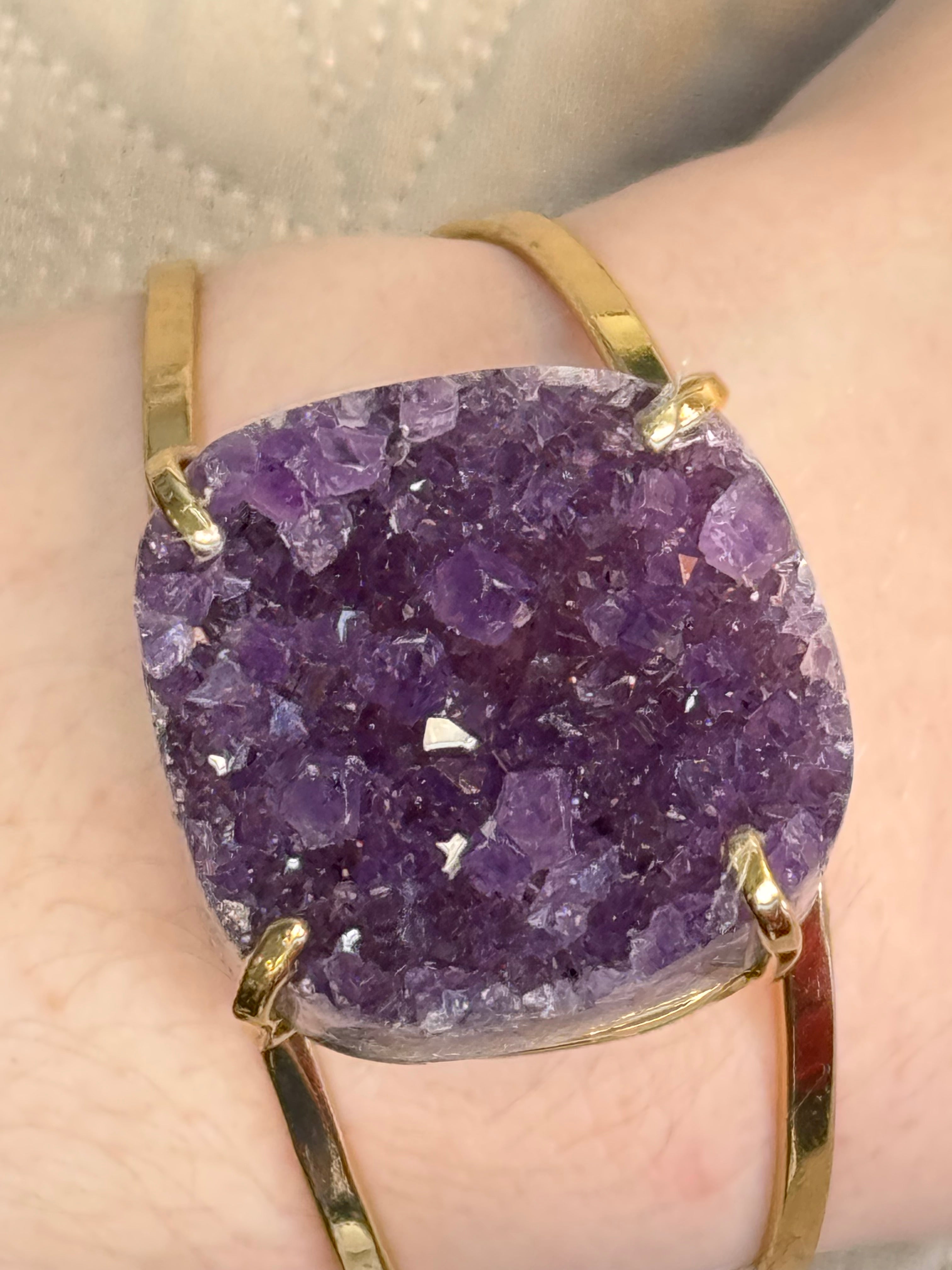 Gold ring with a large purple crystal on a person's finger