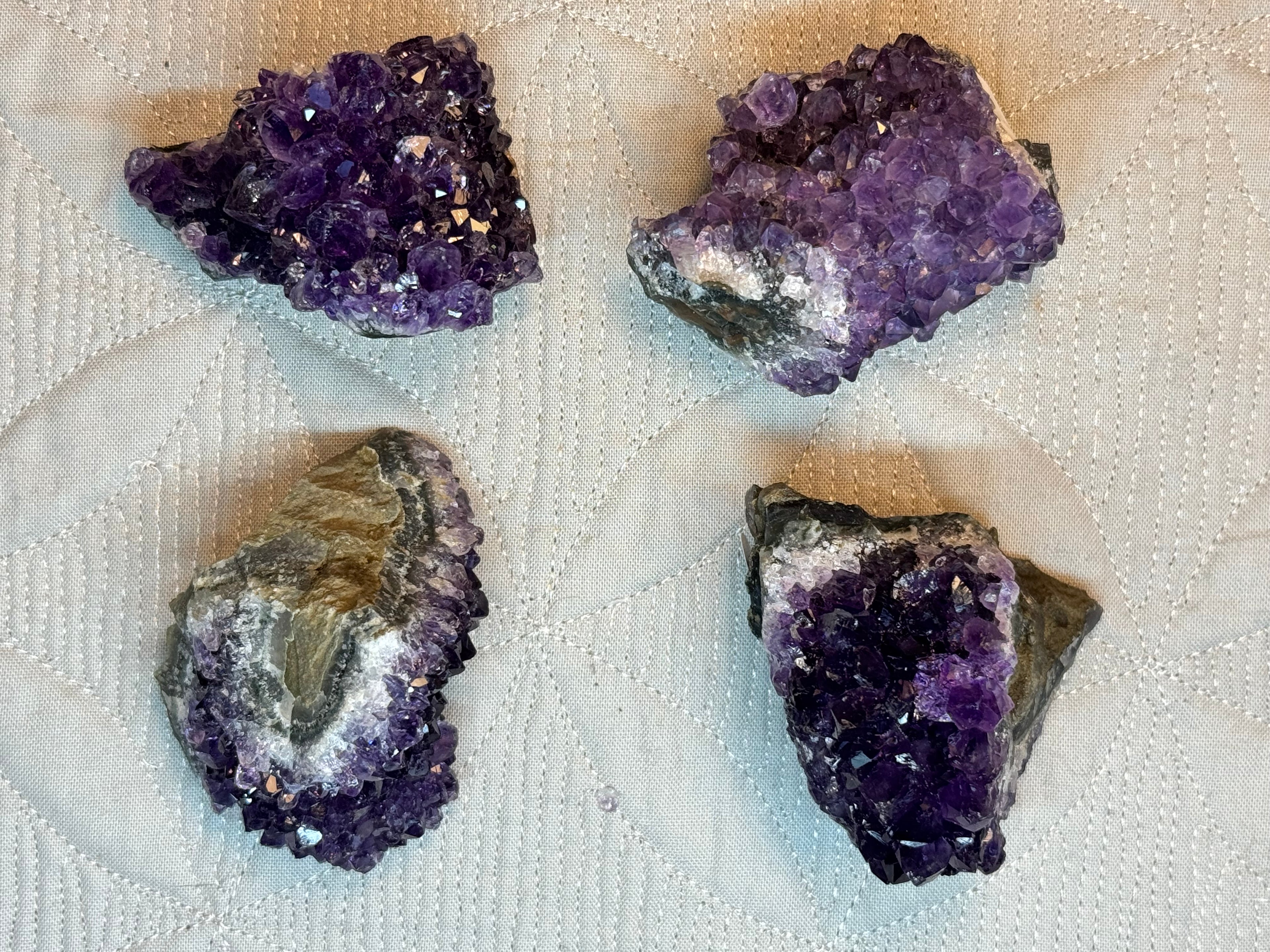 Four purple crystal rocks on a textured white surface