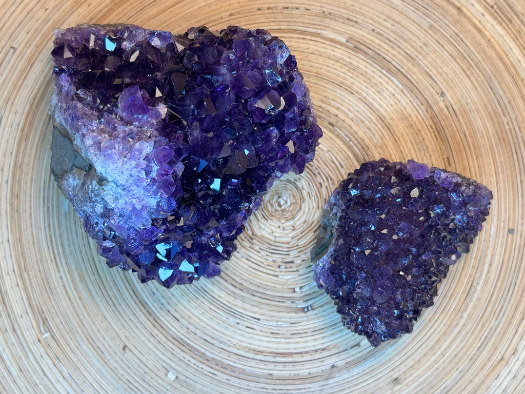 Two purple amethyst crystals on a wooden surface