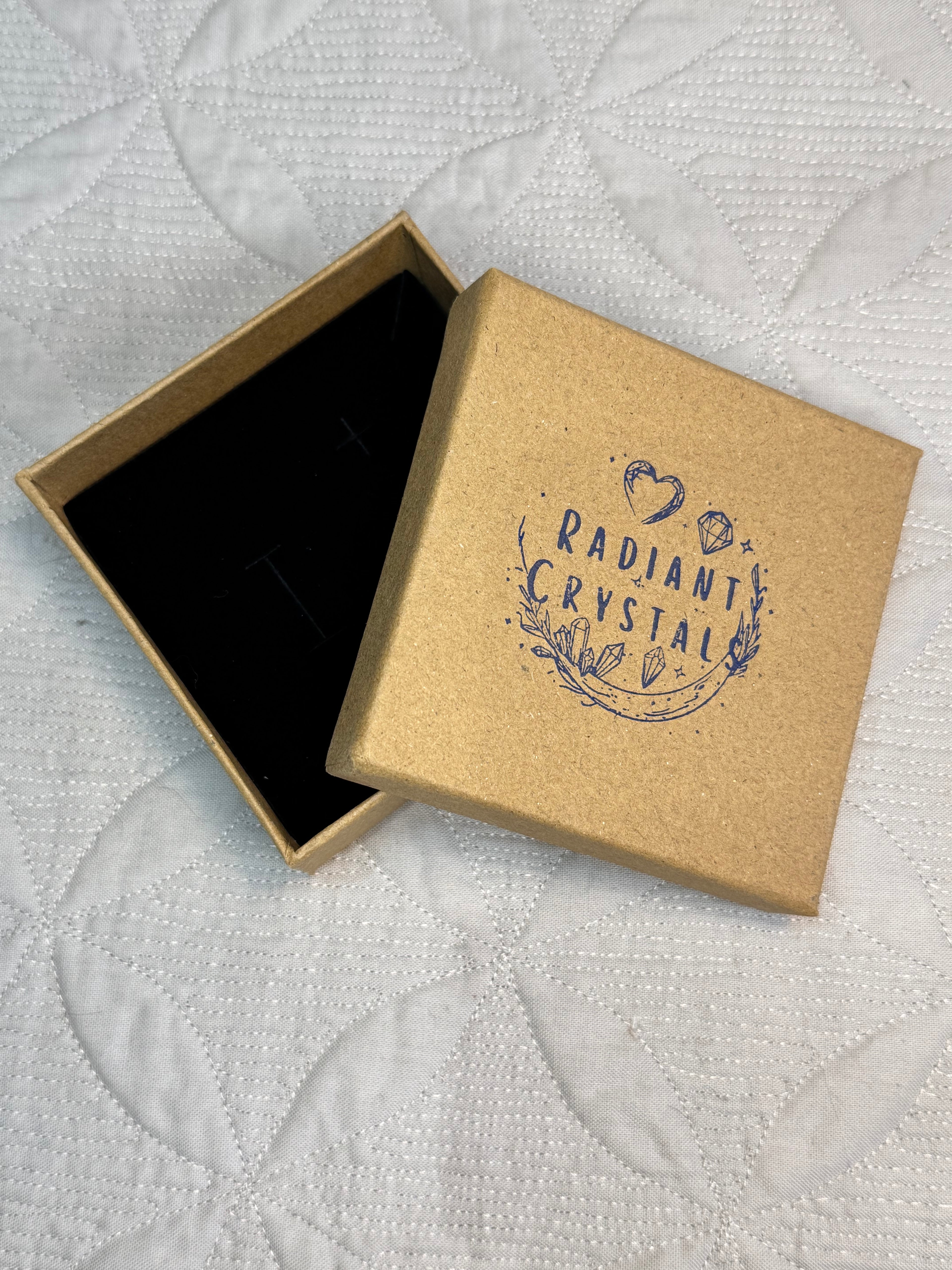 Brown jewelry box with 'Radiant Crystals' branding on a textured white surface
