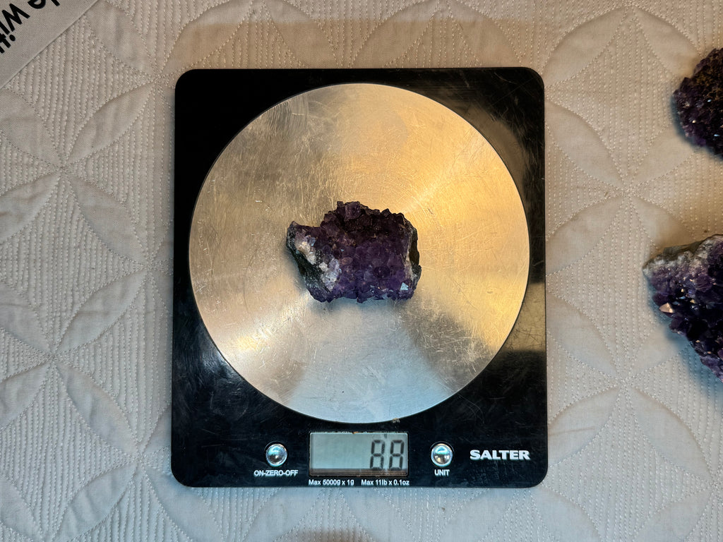 Amethyst crystal on a digital kitchen scale with a textured surface background