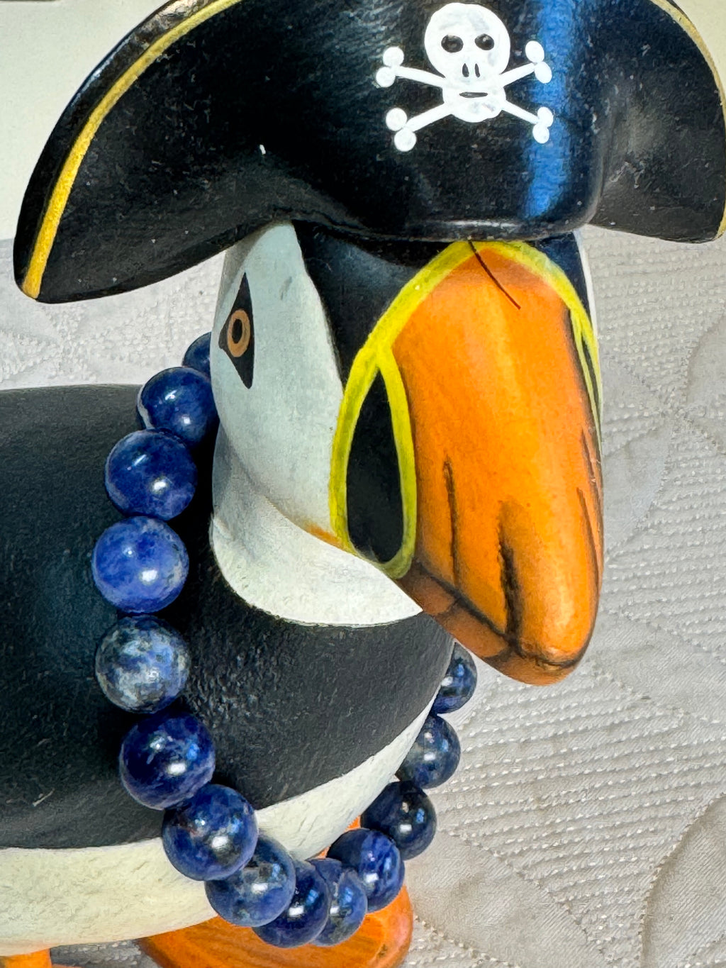 Tuffin figurine with blue sodalite beads on a textured surface