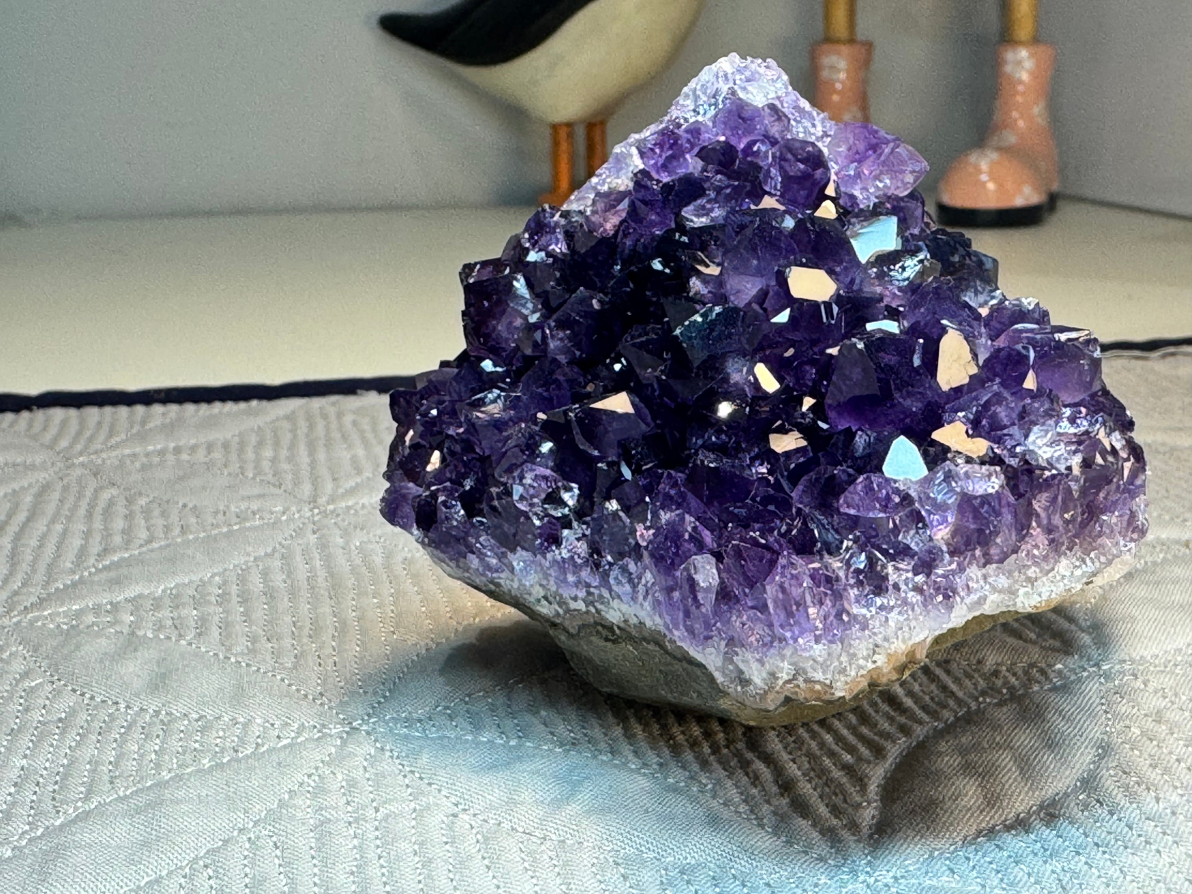 Amethyst crystal cluster on a textured surface with a blurred background