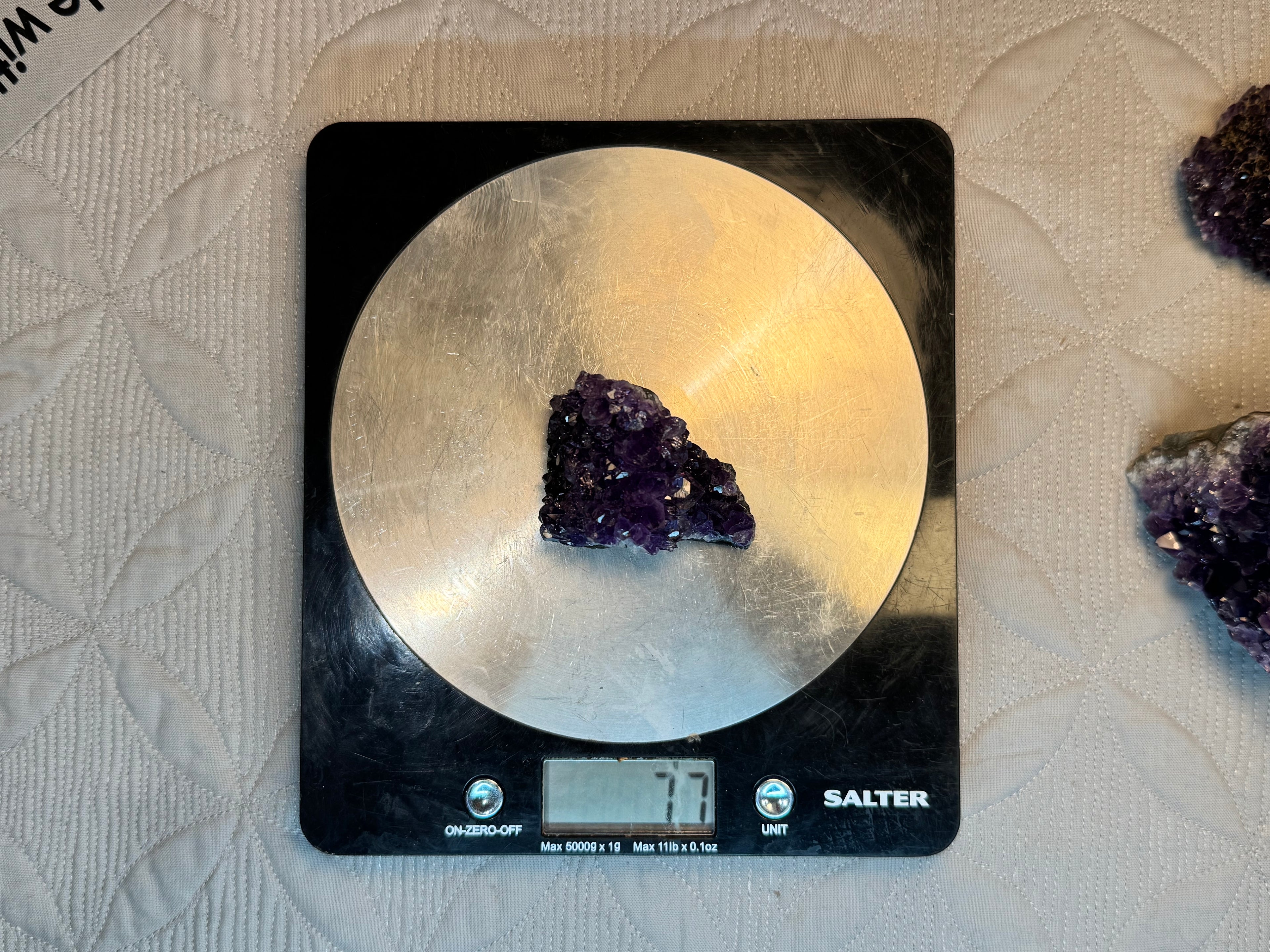 Amethyst crystal on a Salter digital kitchen scale with a textured surface background