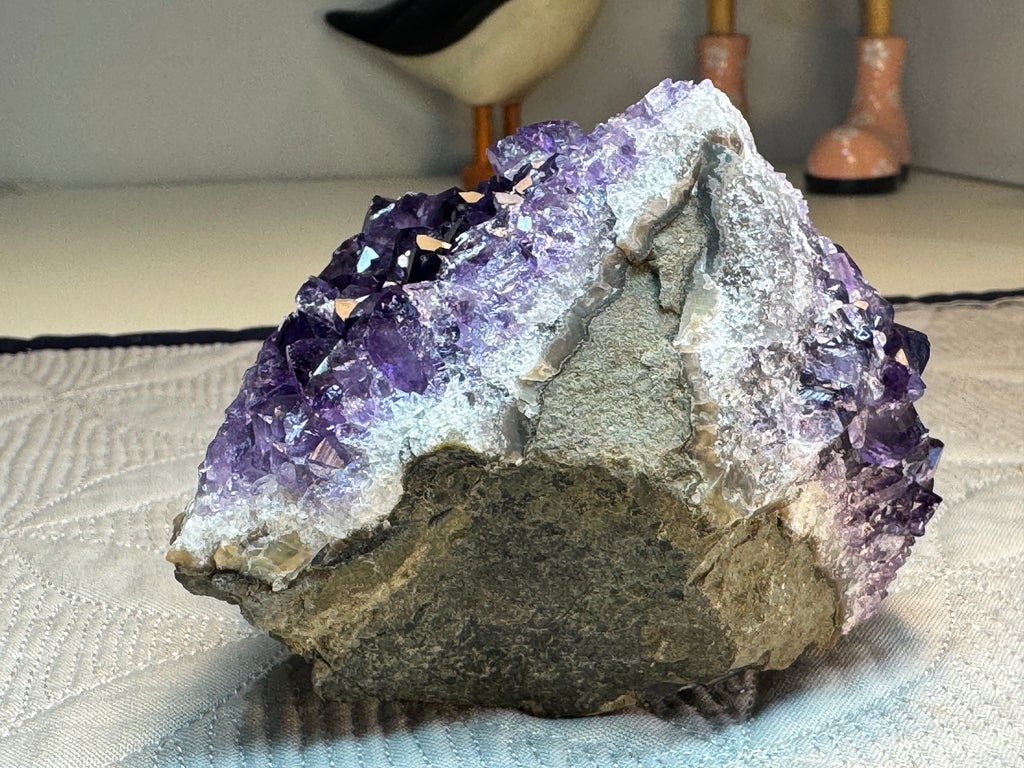 Amethyst crystal on a textured surface with blurred background