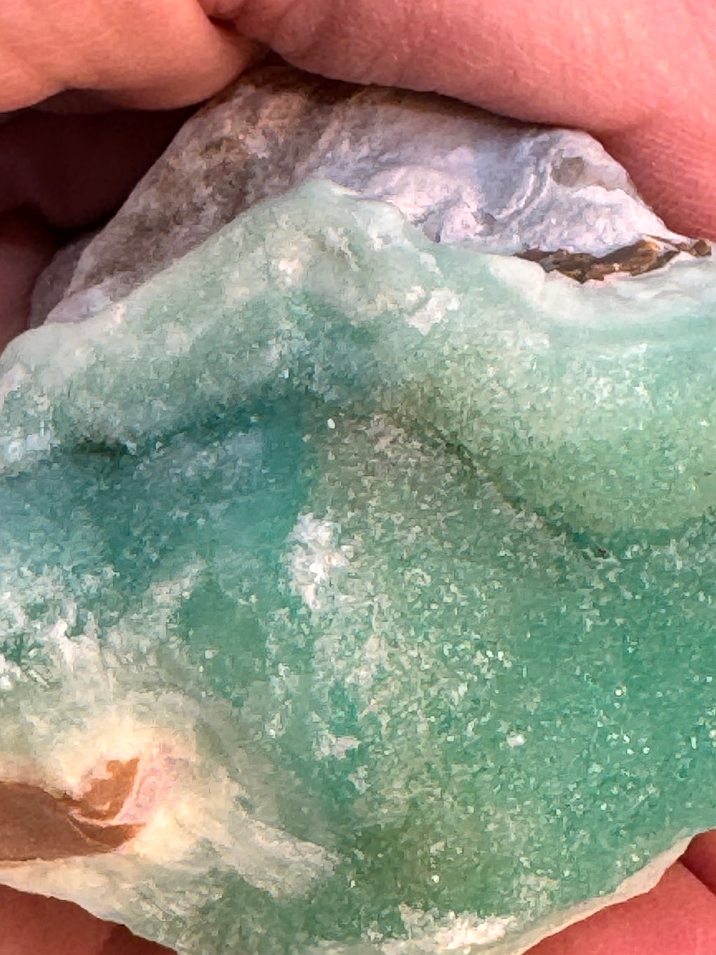 Close-up of a greenish-blue stone held in hands