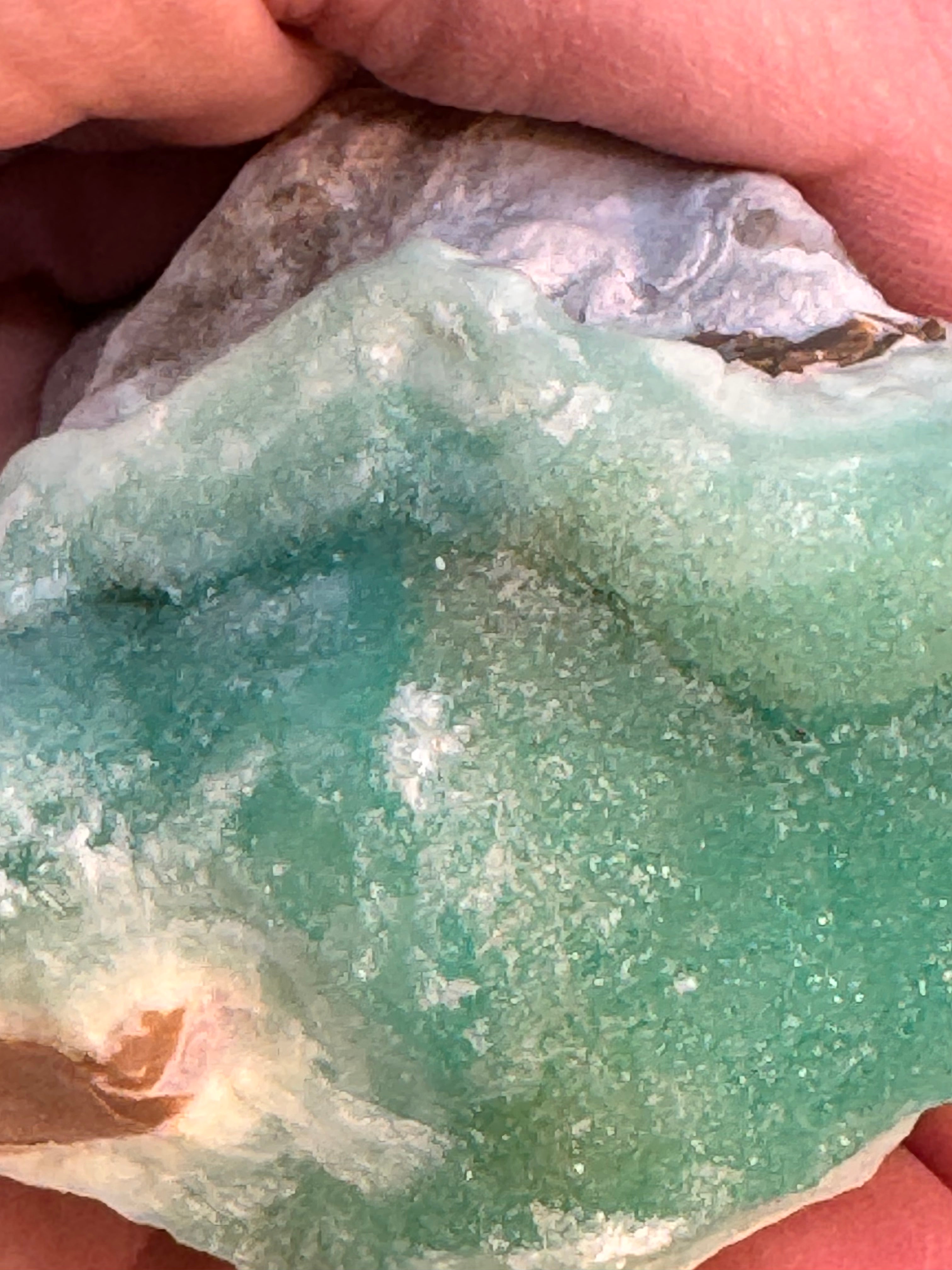 Close-up of a greenish-blue stone held in hands